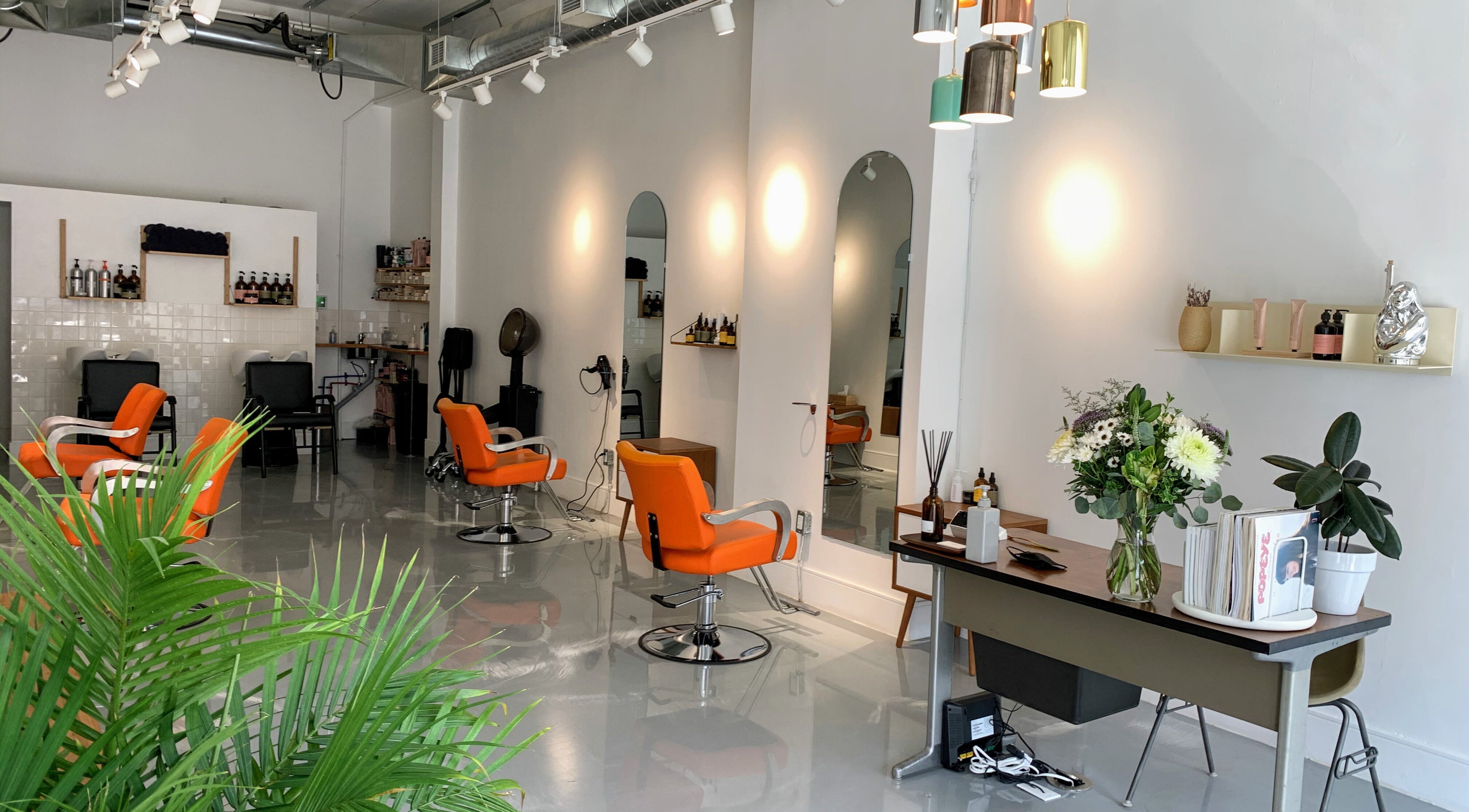 Modern salon interior at Antidote Studio, Toronto, Ontario, CA, featuring stylish orange chairs and sleek decor.