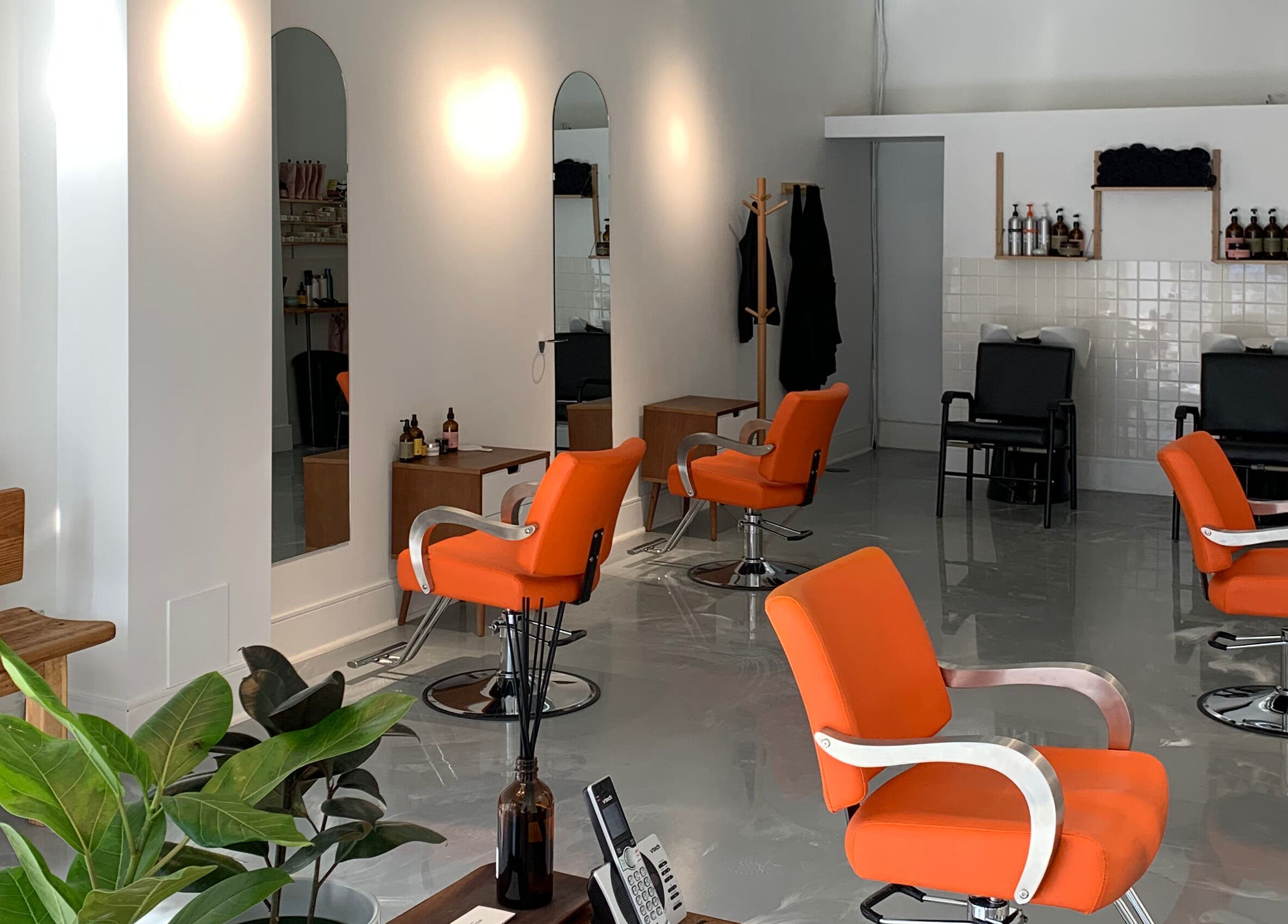 Chic Antidote Studio salon in Toronto, Ontario, CA with modern orange chairs and sleek decor.