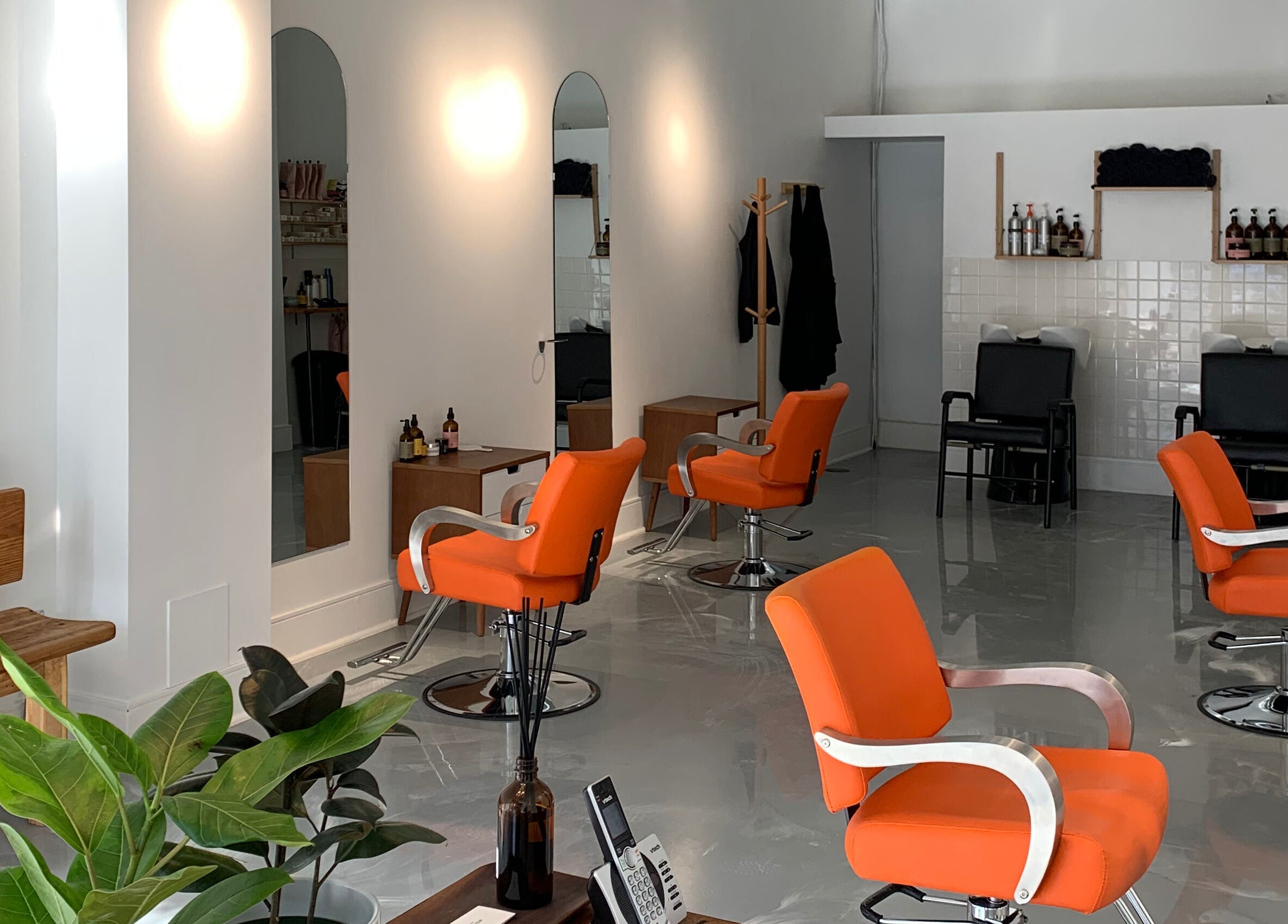 Chic Antidote Studio salon in Toronto, Ontario, CA with modern orange chairs and sleek decor.