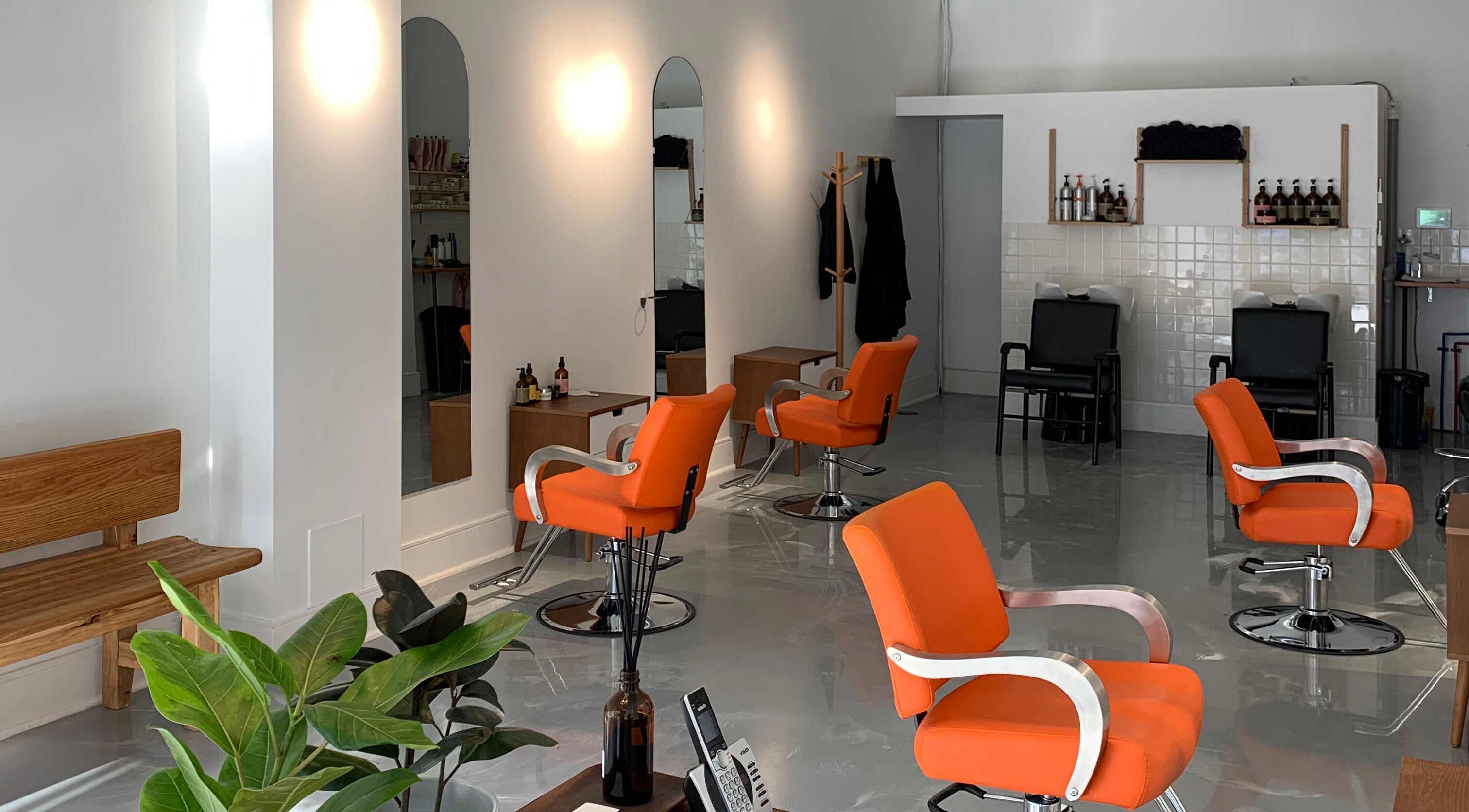 Chic Antidote Studio salon in Toronto, Ontario, CA with modern orange chairs and sleek decor.