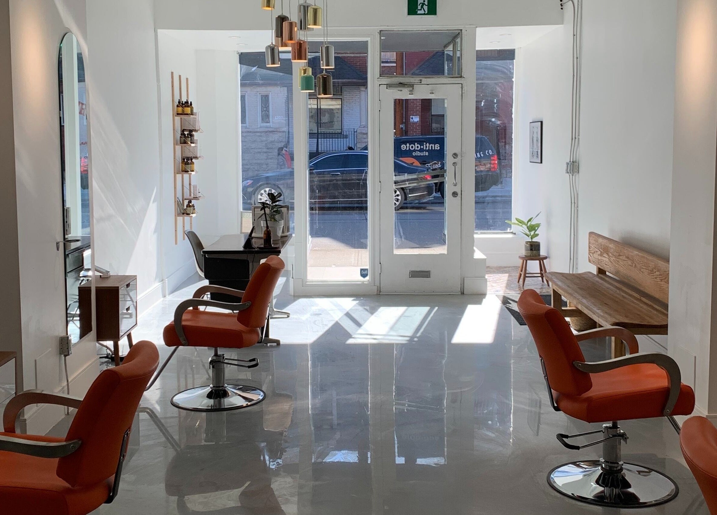 Modern salon interior at Antidote Studio, Toronto, Ontario, CA, featuring stylish orange chairs and sleek design.