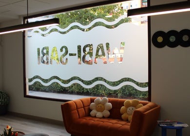 Interior de Wabi-Sabi en Albacete, Castilla-la Mancha, ES, con un sofá naranja y ventanas decorativas.