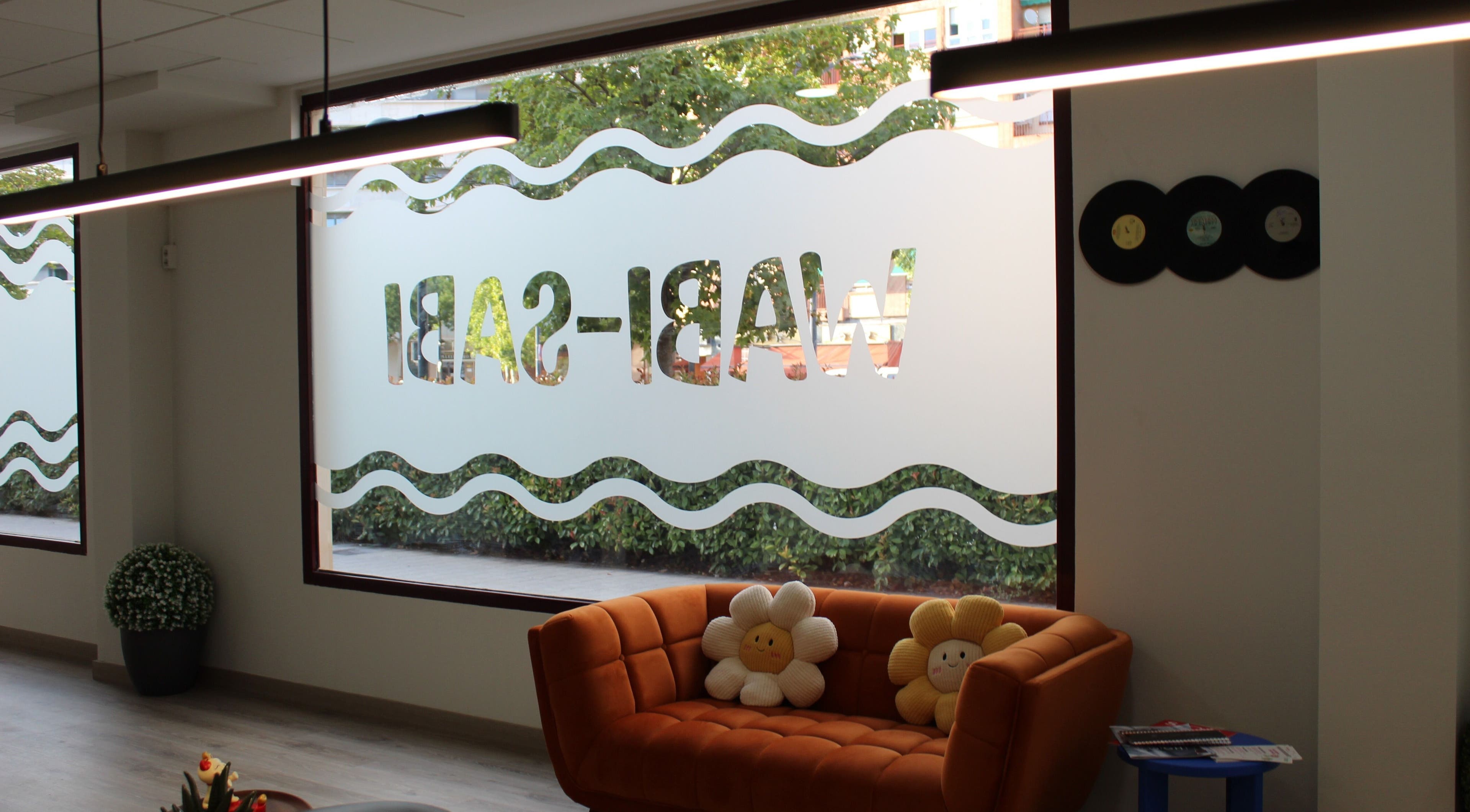 Interior de Wabi-Sabi en Albacete, Castilla-la Mancha, ES, con un sofá naranja y ventanas decorativas.