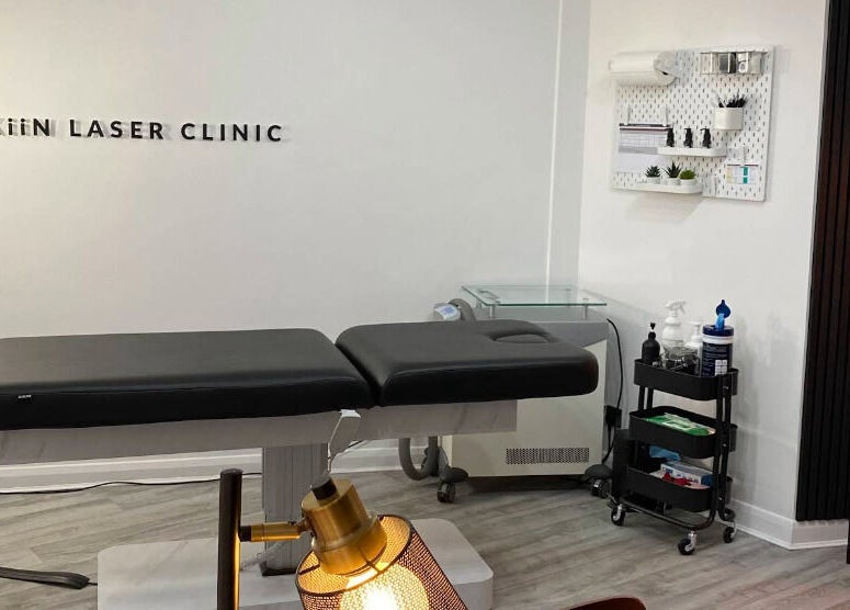 Skiin Laser Clinic treatment room in Peterborough, England, GB, featuring a modern massage table and decor.