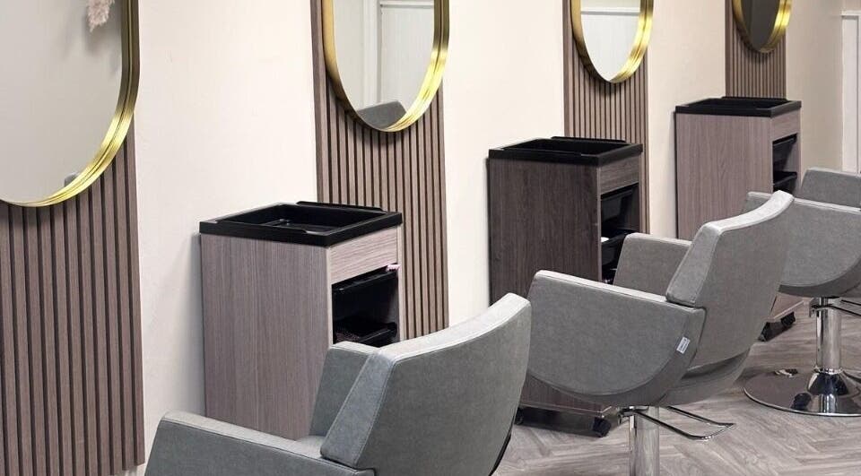 Modern salon chairs and mirrors at Caine Moore Hair, Egremont, England, GB, showcasing sleek design.