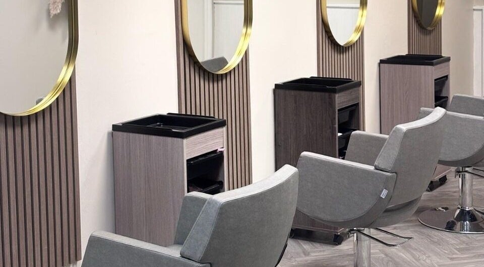 Modern salon chairs and mirrors at Caine Moore Hair, Egremont, England, GB, showcasing sleek design.