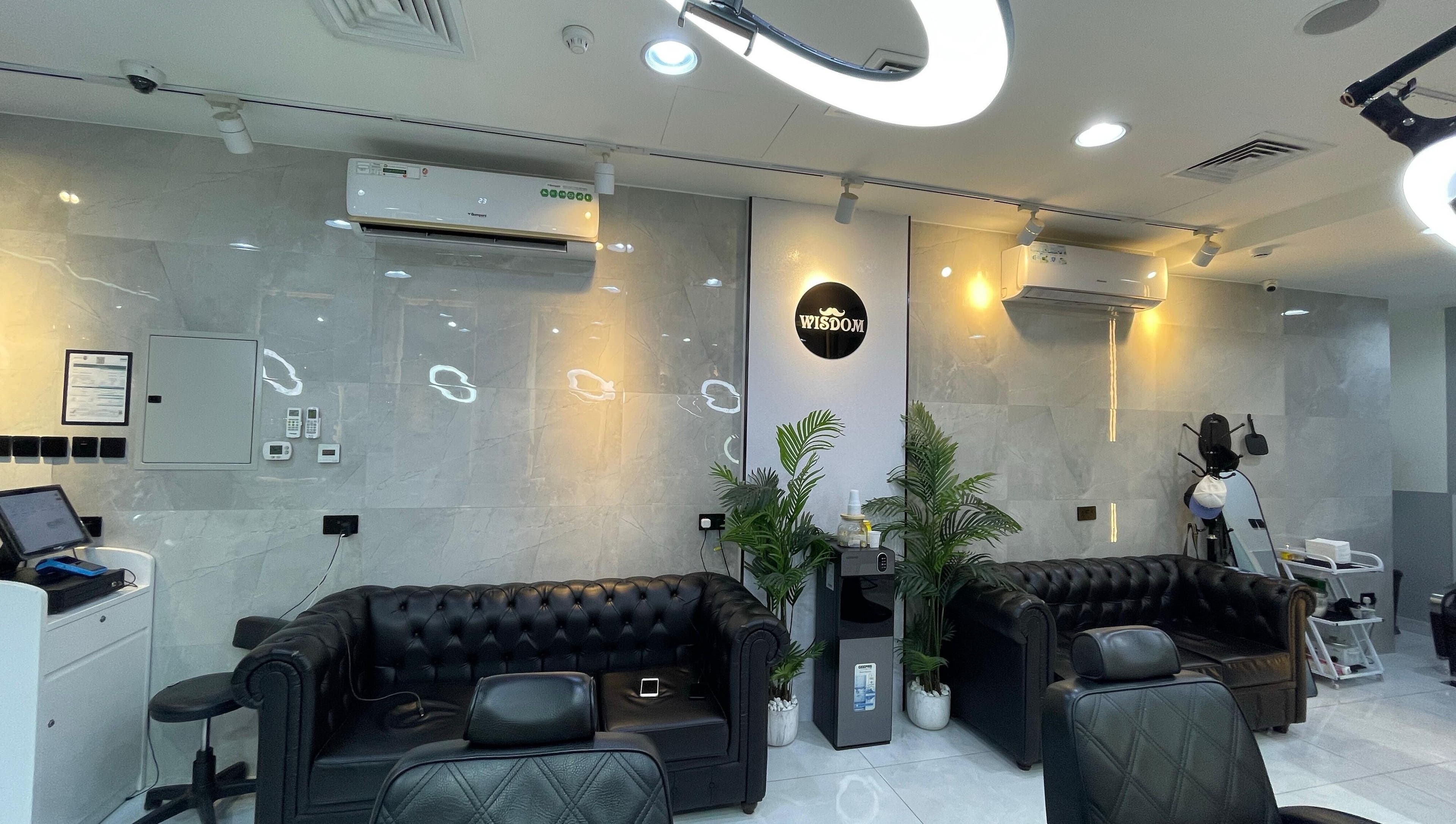 Modern seating area at Wisdom Gents Saloon, Dubai, AE with sleek leather couches and vibrant plants.