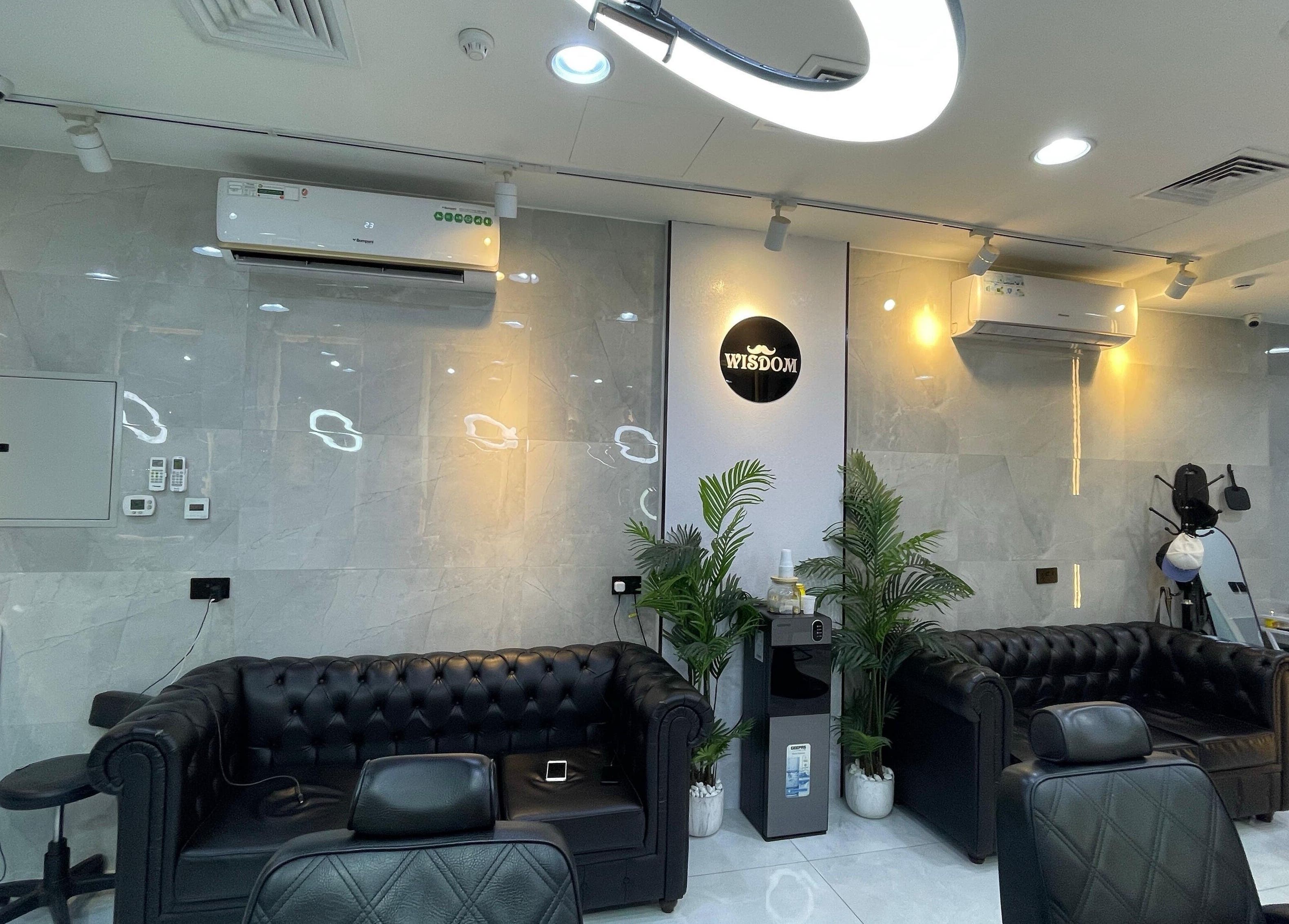 Modern seating area at Wisdom Gents Saloon, Dubai, AE with sleek leather couches and vibrant plants.