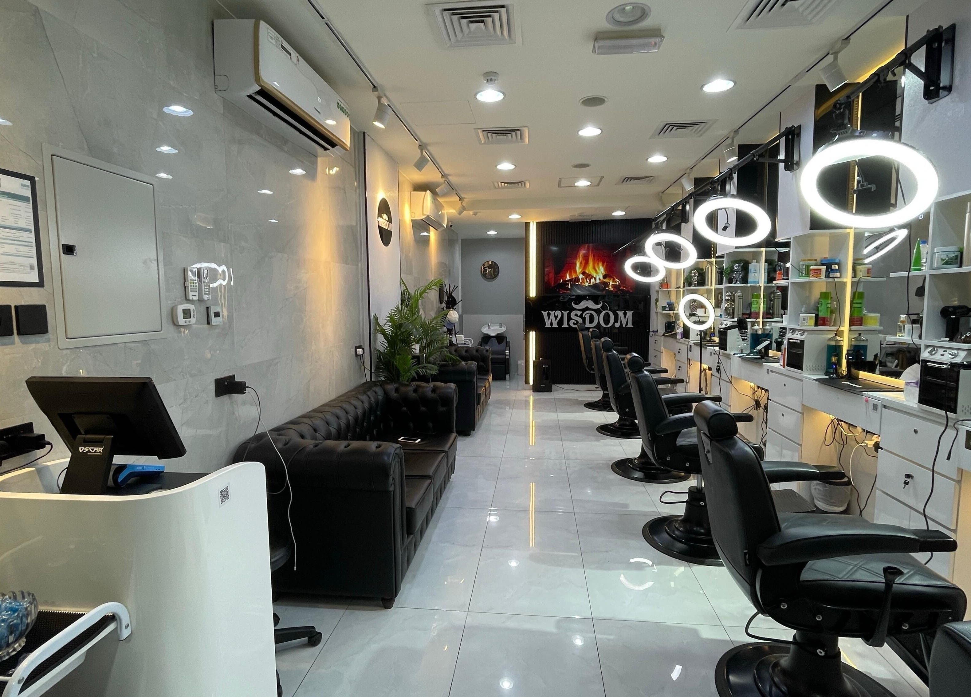 Sleek interior of Wisdom Gents Saloon in Dubai, AE with stylish black chairs and illuminated mirrors.
