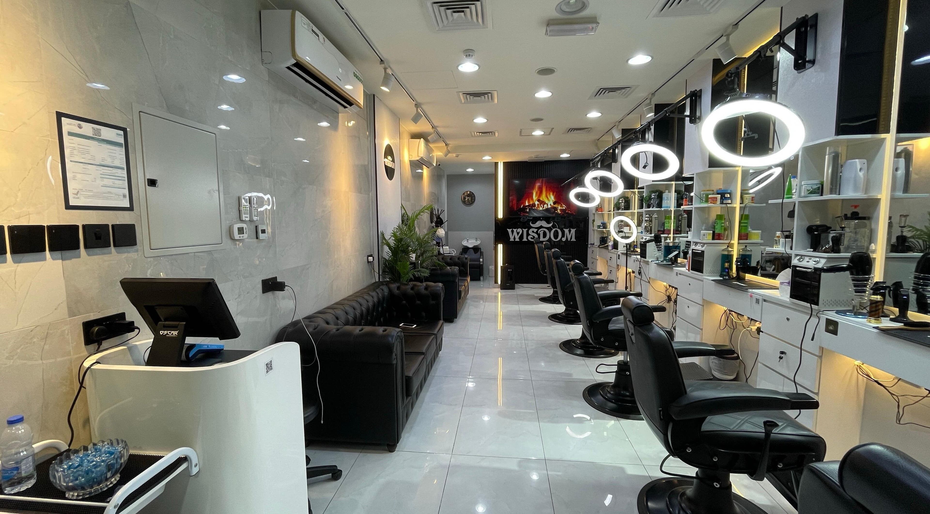 Sleek interior of Wisdom Gents Saloon in Dubai, AE with stylish black chairs and illuminated mirrors.