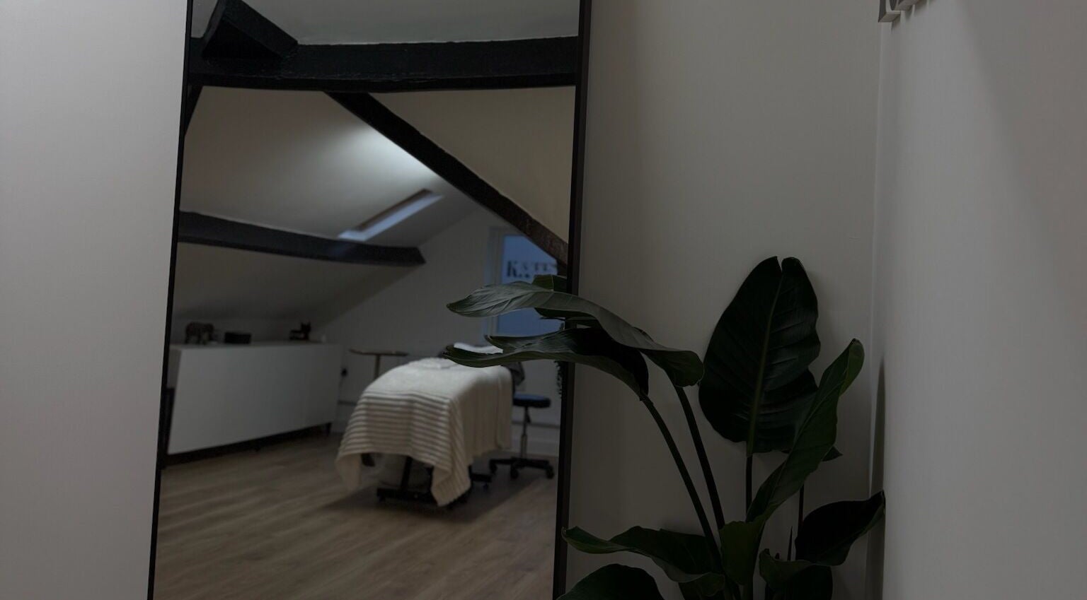 Elegant spa room at Kate's Studio, Coalville, England with a massage table and lush plant decor.
