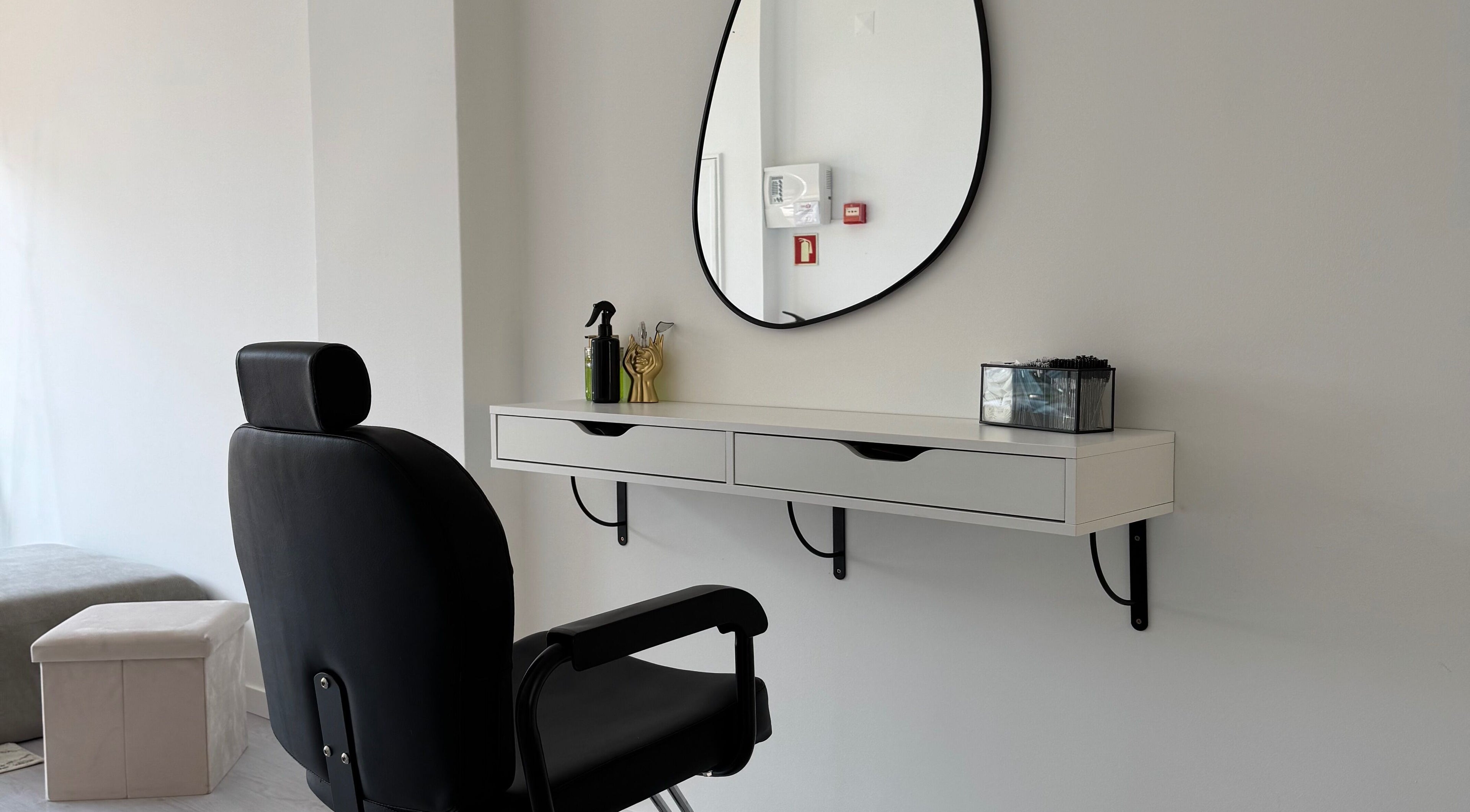 Espaço de salão moderno em Juliana Nailstylist, Barcelos, Braga, PT, com espelho e cadeira preta.