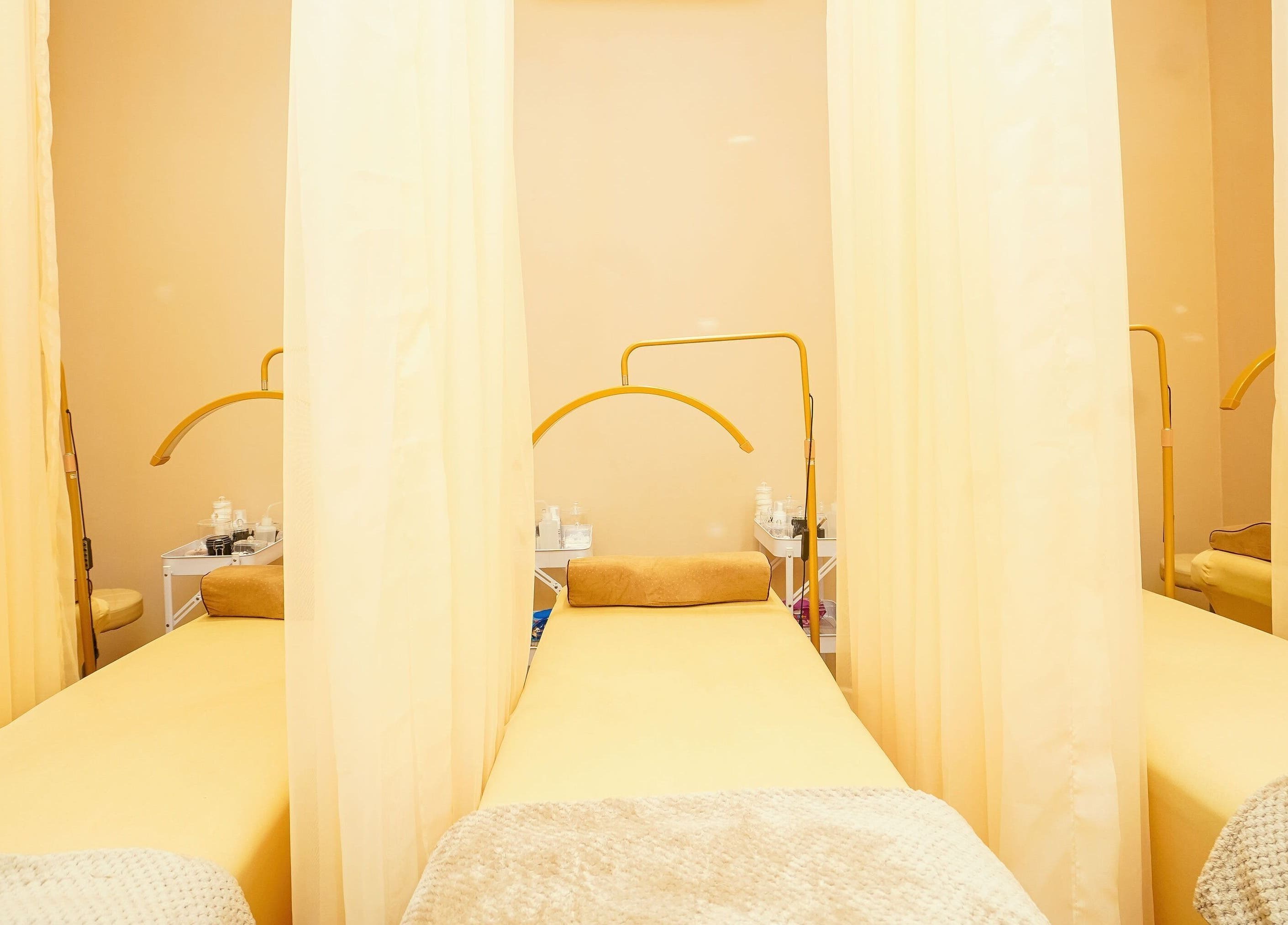 Peaceful Lash Room in Lagos, Lagos, NG showcasing comfortable treatment beds with soft yellow curtains.