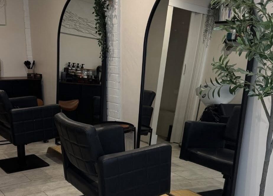 Modern salon seating at By Evangeline, Plymouth, England, GB with sleek mirrors and plant decor.