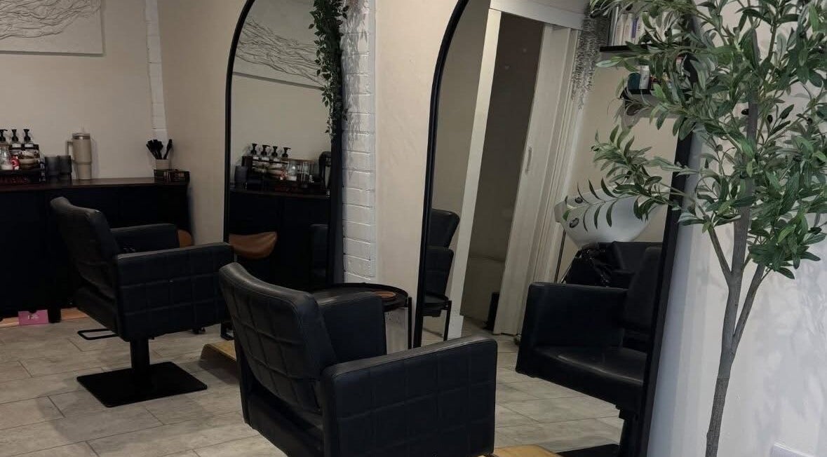 Modern salon seating at By Evangeline, Plymouth, England, GB with sleek mirrors and plant decor.