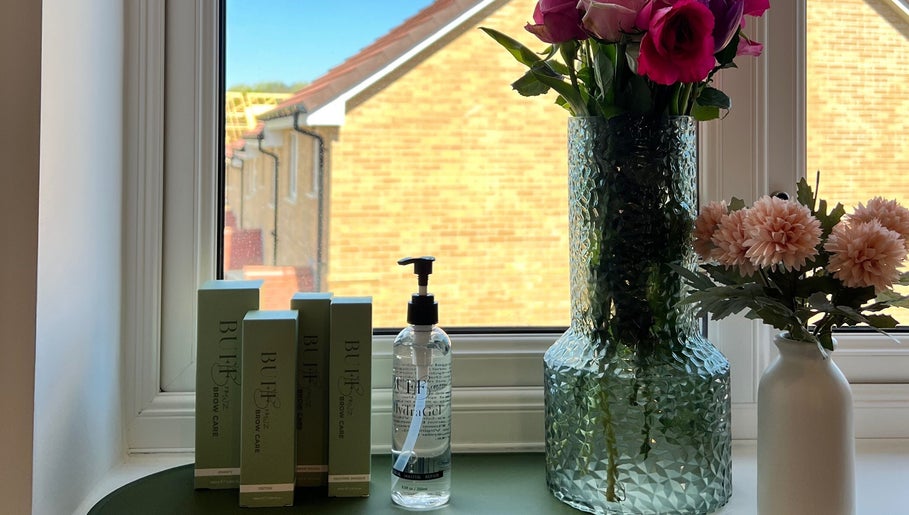 Elegant window setup at Neve Amelia Beauty, Daventry, England, GB with beauty products and floral decor.
