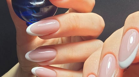 French manicure at Nataliia Demi Nails, London, England, GB. Close-up of elegant nails holding a blue bottle.