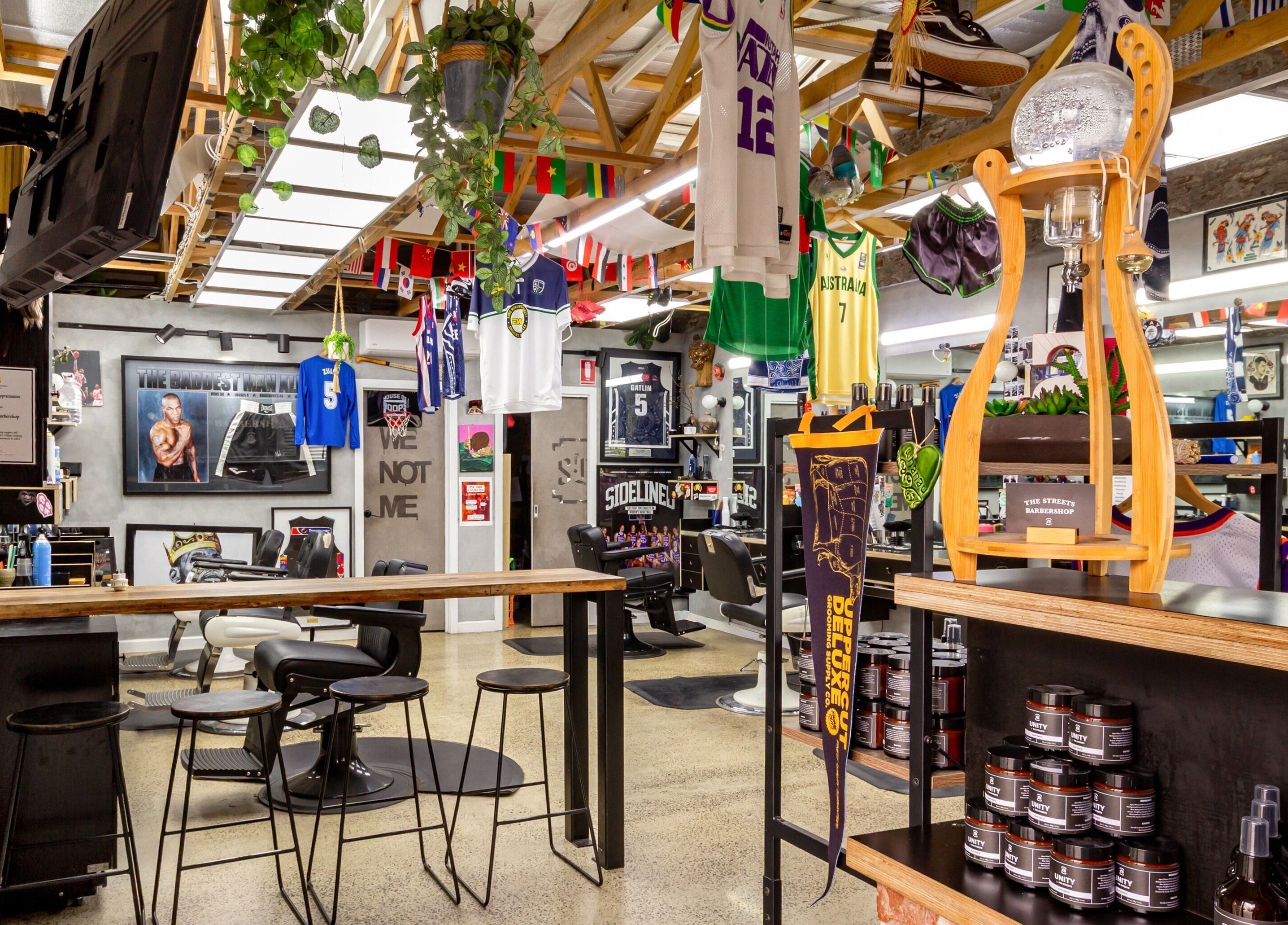 Vibrant interior of The Streets Barbershop in Geelong West, Victoria with sports decor and modern styling chairs.