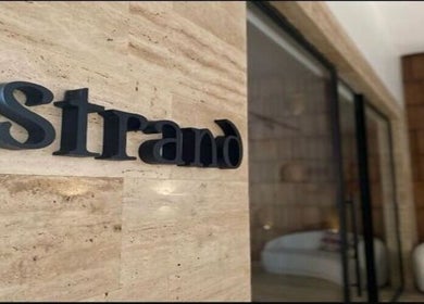 Entrance of Strand Salon in Riyadh, Riyadh Province, SA, with logo on stone wall.