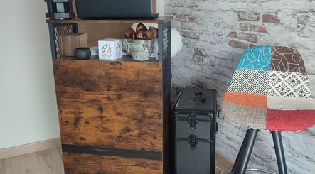 Intérieur chaleureux de Chez Sonia / A Chacun Ses Ongles à Moëlan-sur-mer, Bretagne, FR, avec chaise patchwork colorée.