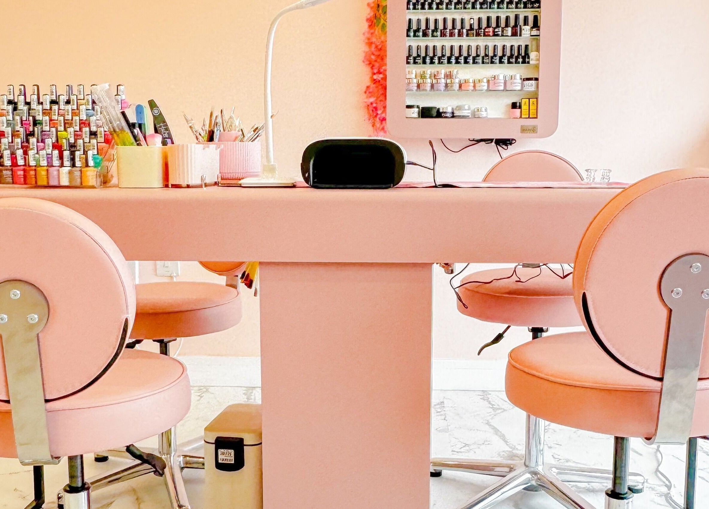 Elegant nail station at GK Beauty in Maltby, England, GB, featuring pink chairs and nail polish display.