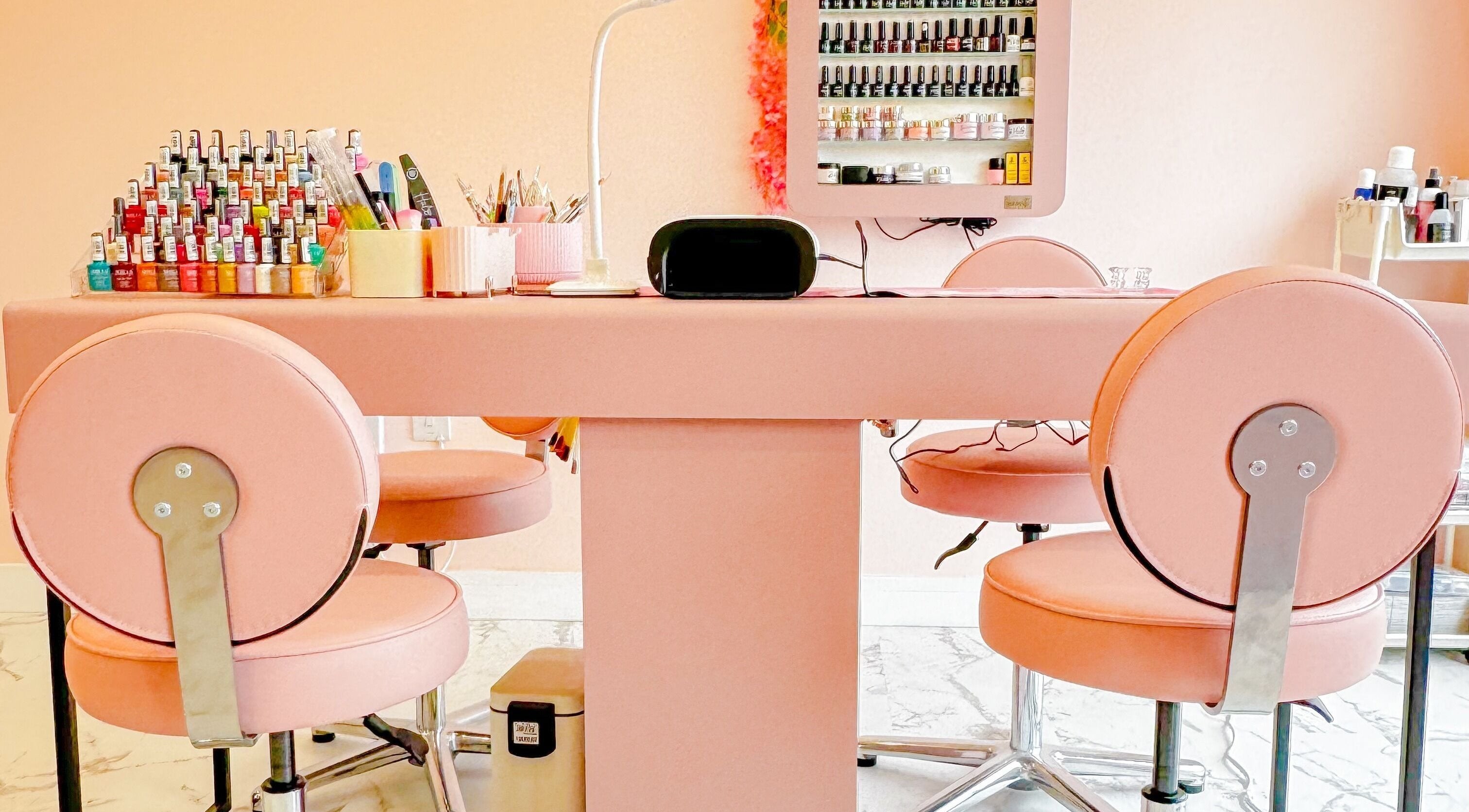 Elegant nail station at GK Beauty in Maltby, England, GB, featuring pink chairs and nail polish display.