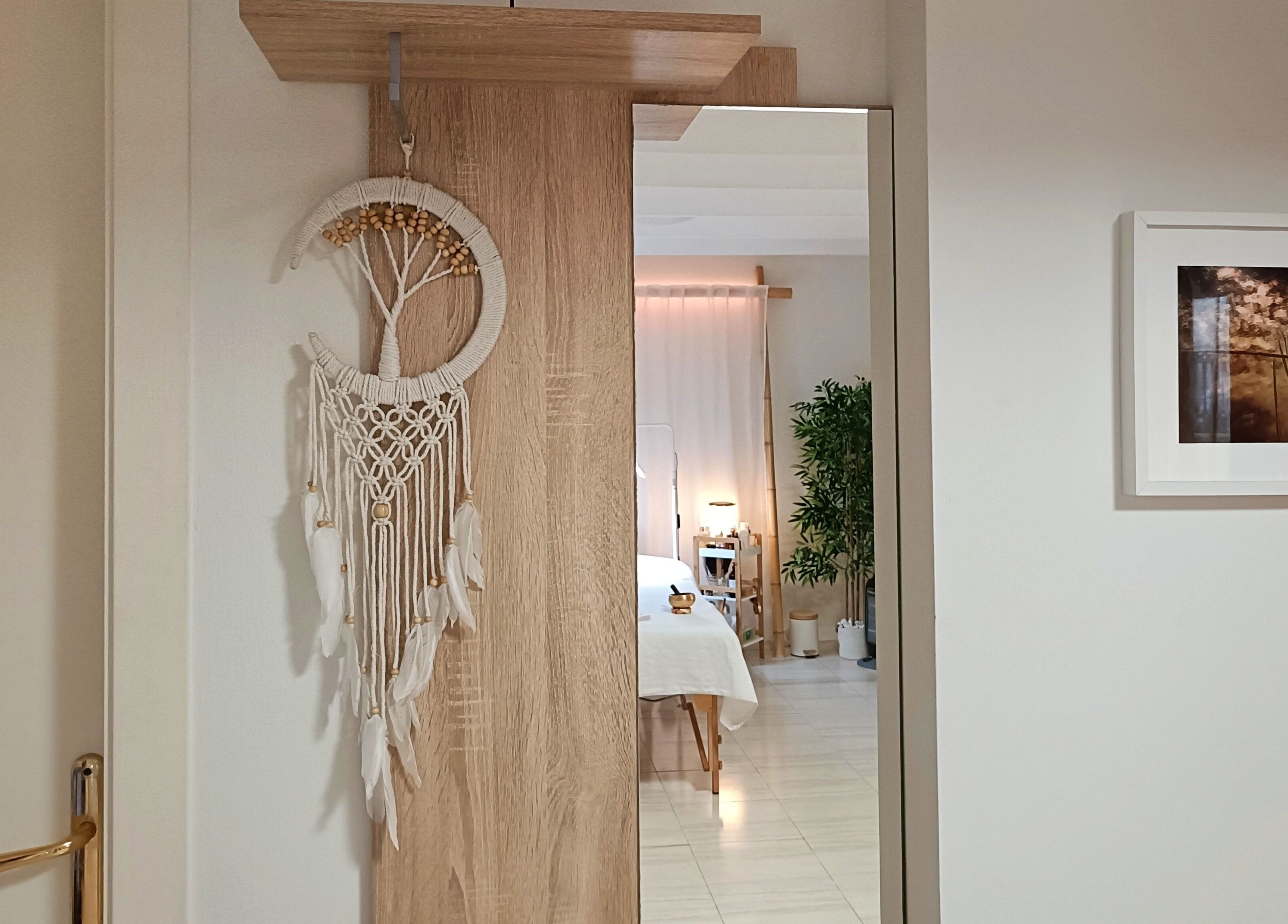 Entrada serena en Cara Sana, Barcelona, mostrando un colgante macramé y vista parcial de la sala de tratamiento.