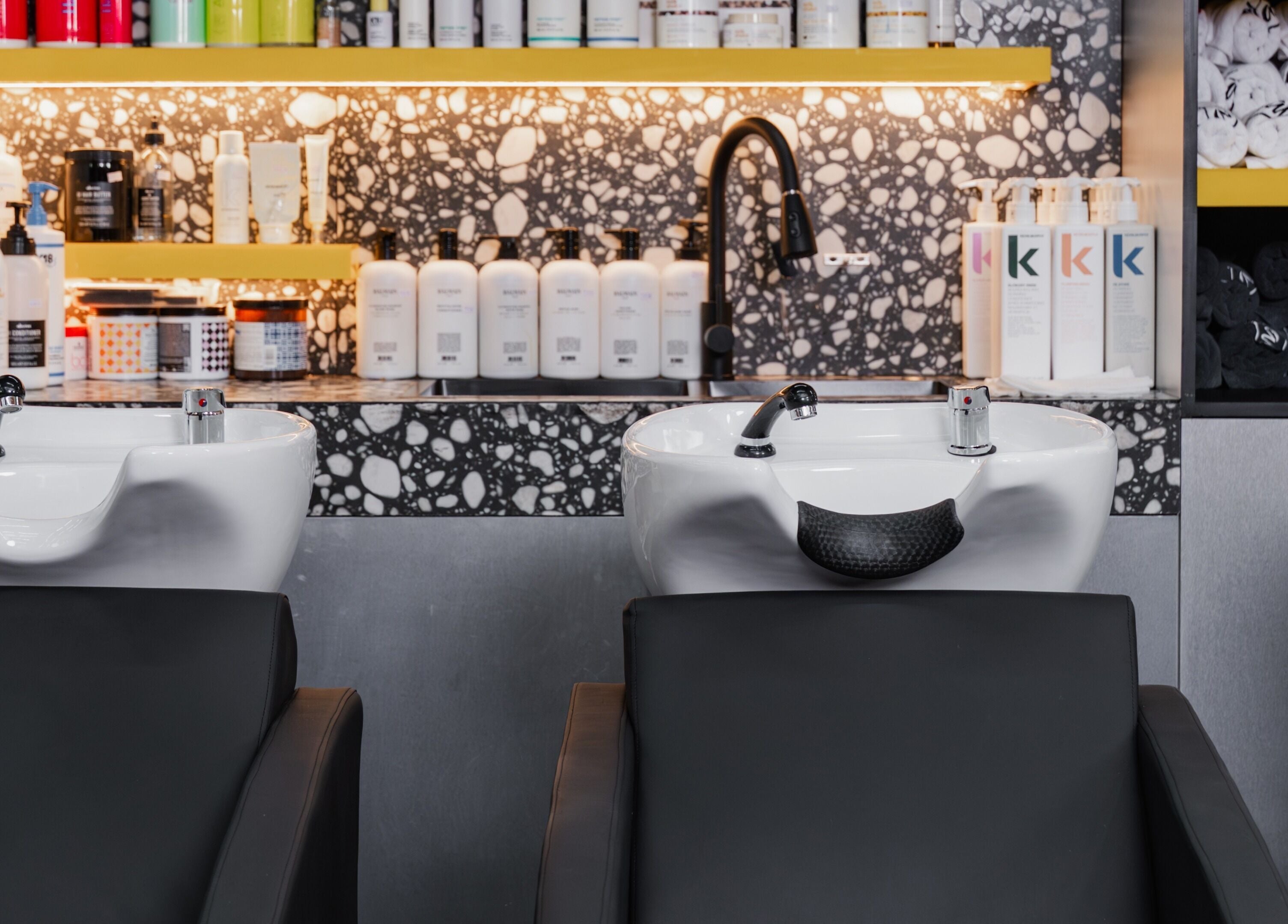 Luxurious shampooing area at Elated, Abu Dhabi, AE featuring modern sinks and premium hair products.
