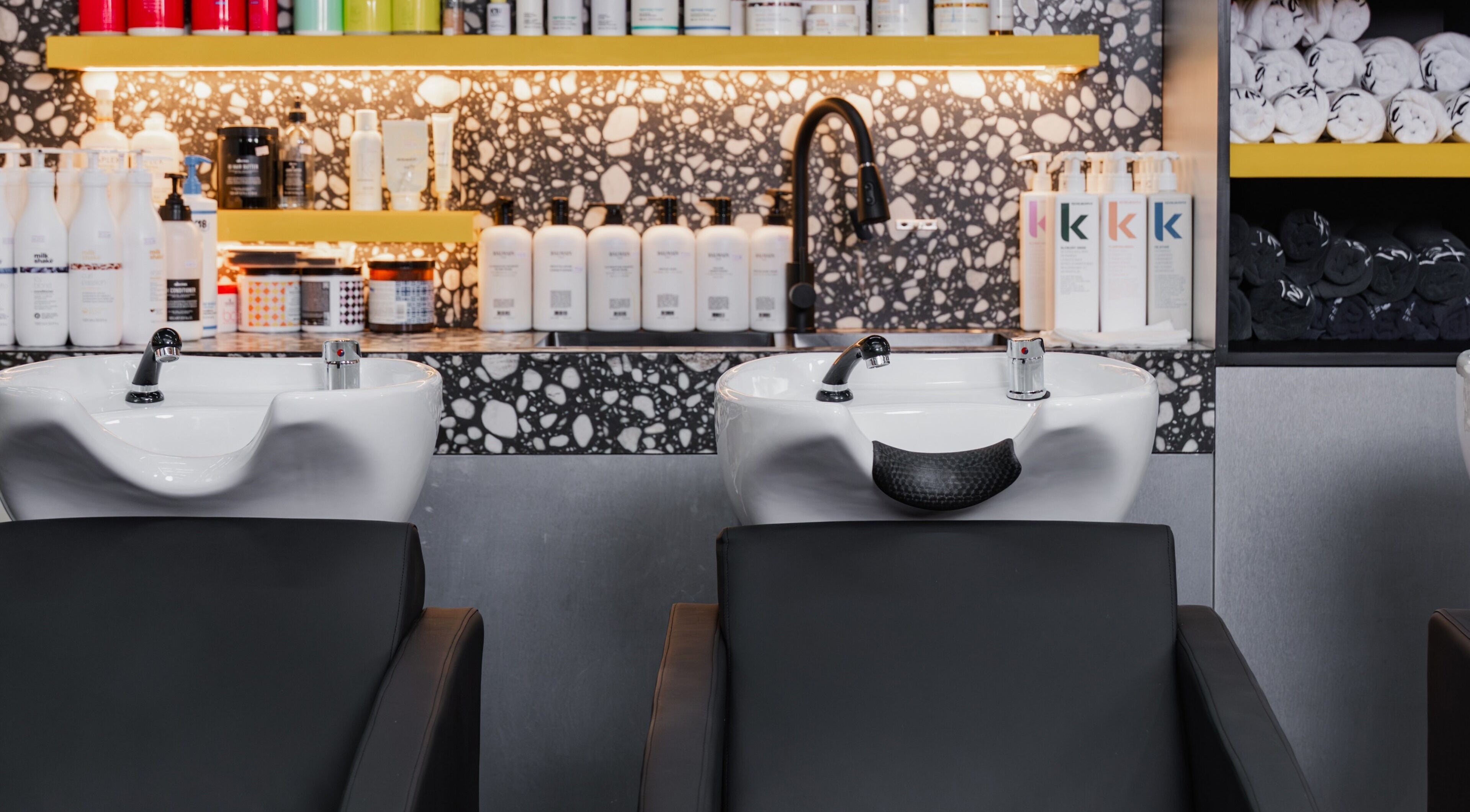 Luxurious shampooing area at Elated, Abu Dhabi, AE featuring modern sinks and premium hair products.