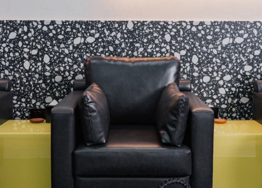 Comfortable black leather seating at Elated, Abu Dhabi, AE, with modern patterned wall and side tables.