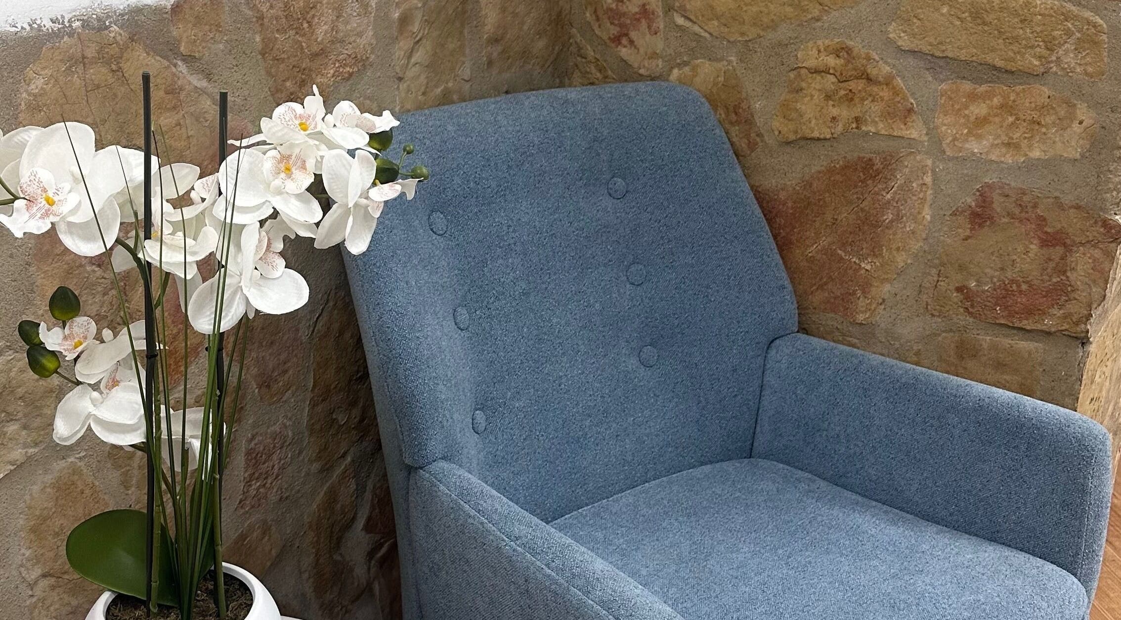 Cómoda silla azul junto a orquídea blanca en HydroEstetic, València, Comunidad Valenciana, ES.
