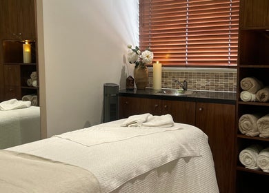 Cozy treatment room at Tranquility By Catalin, featuring candles, towels, and flowers in Bridgend, Wales, GB.