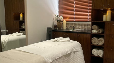 Cozy treatment room at Tranquility By Catalin, featuring candles, towels, and flowers in Bridgend, Wales, GB.