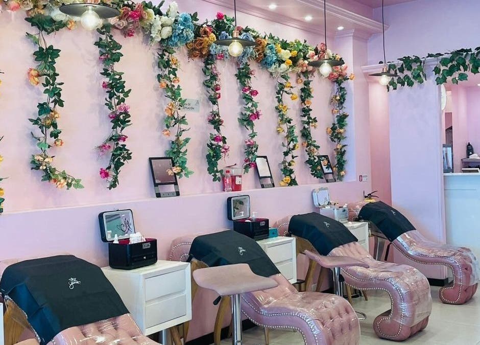 Elegante área de estética en Glam Spa Bogotá - Sede Restrepo con paredes florales y sillones rosados, Bogotá, D.c., CO.