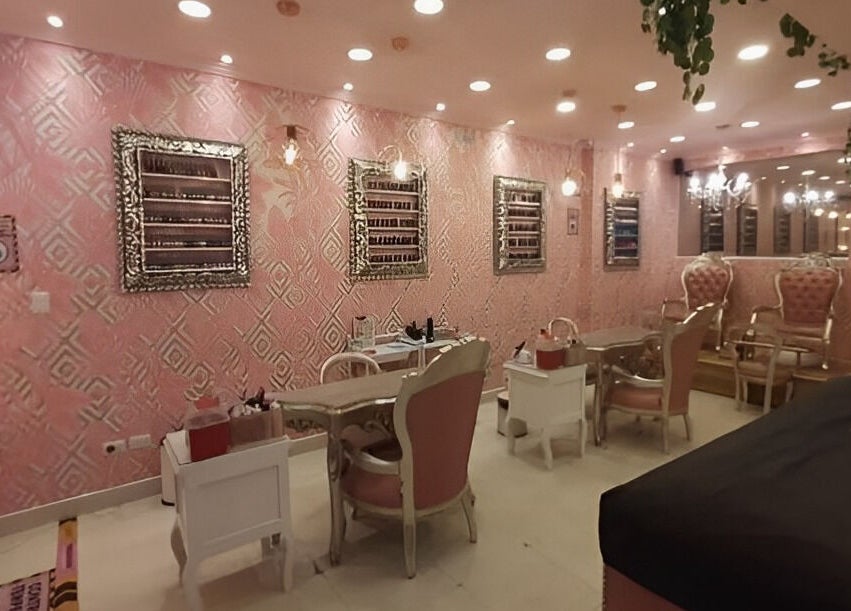 Interior elegante de Glam Spa Bogota - Sede Chicó en Bogotá, CO, con sillas rosas y espejos glamorosos.