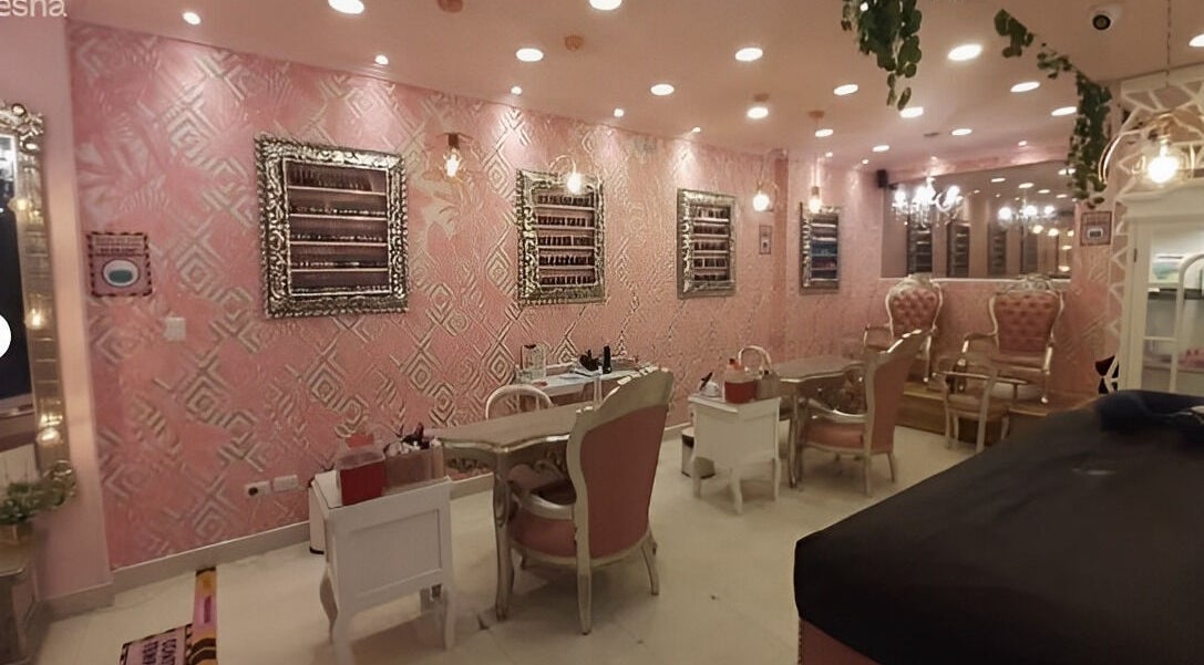 Interior elegante de Glam Spa Bogota - Sede Chicó en Bogotá, CO, con sillas rosas y espejos glamorosos.