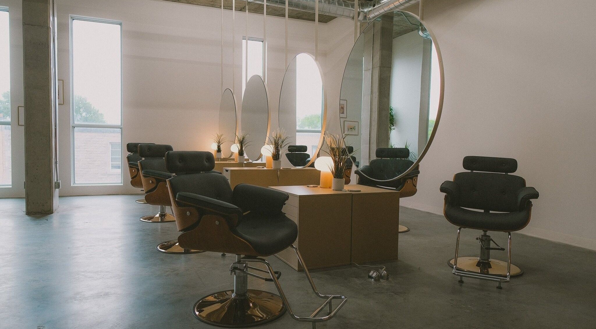 Intérieur moderne de Coiffure Dominique à Montréal, Québec, CA, avec des miroirs ovales et des fauteuils stylés.