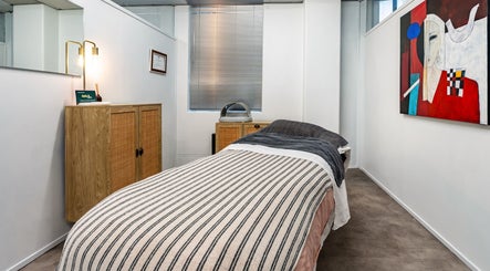 Cozy treatment room at Beauty Refinery in Auckland, Auckland, NZ, featuring a striped massage table and vibrant artwork.