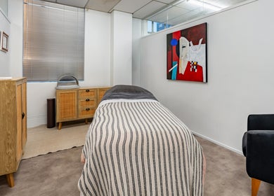 Serene treatment room at Beauty Refinery, Auckland, NZ with cozy decor and artistic wall painting.
