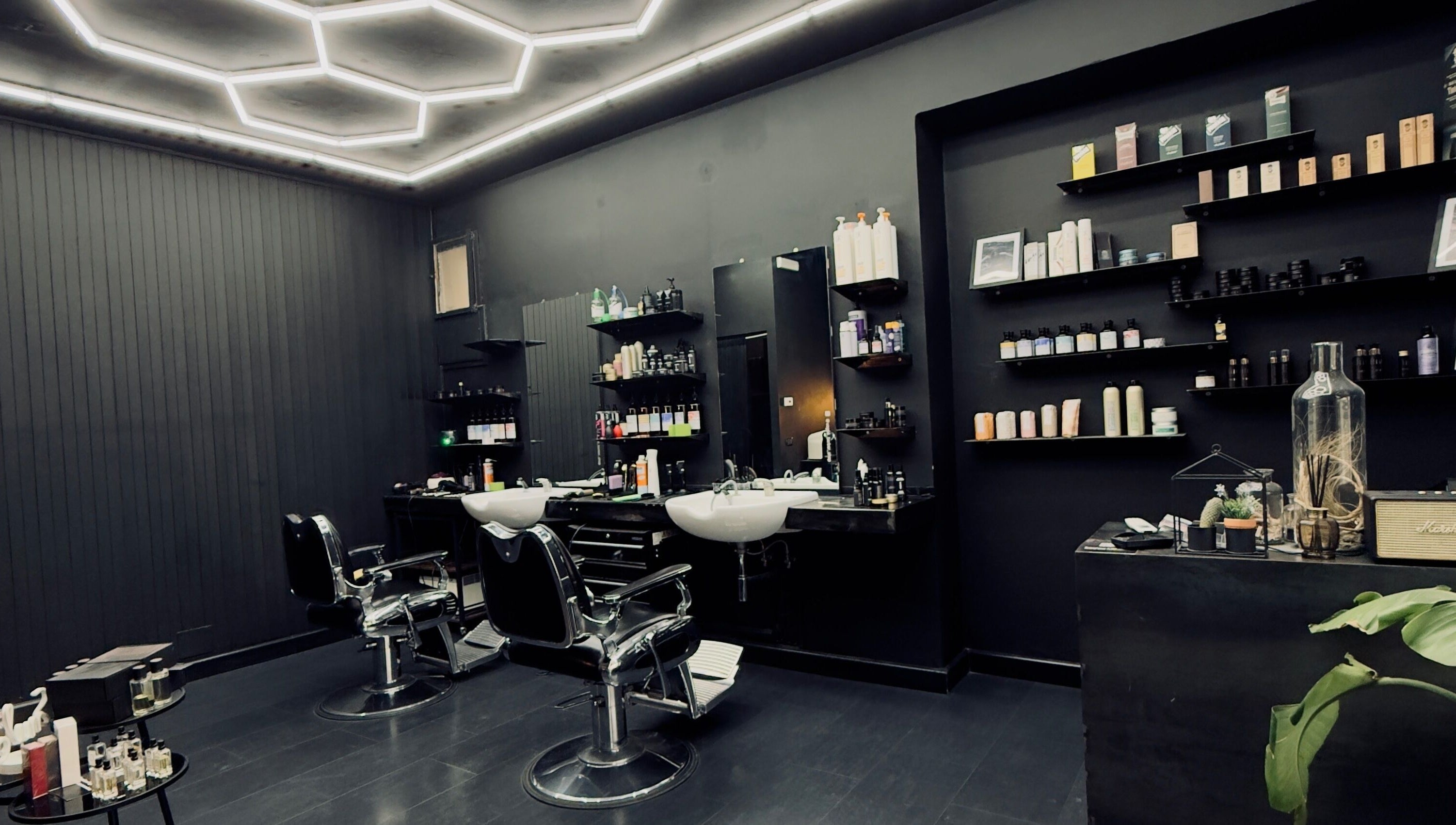 Interno moderno di Vogue Barber Shop, Arceto, Emilia-Romagna, IT con sedie e mensole elegantemente arredate.