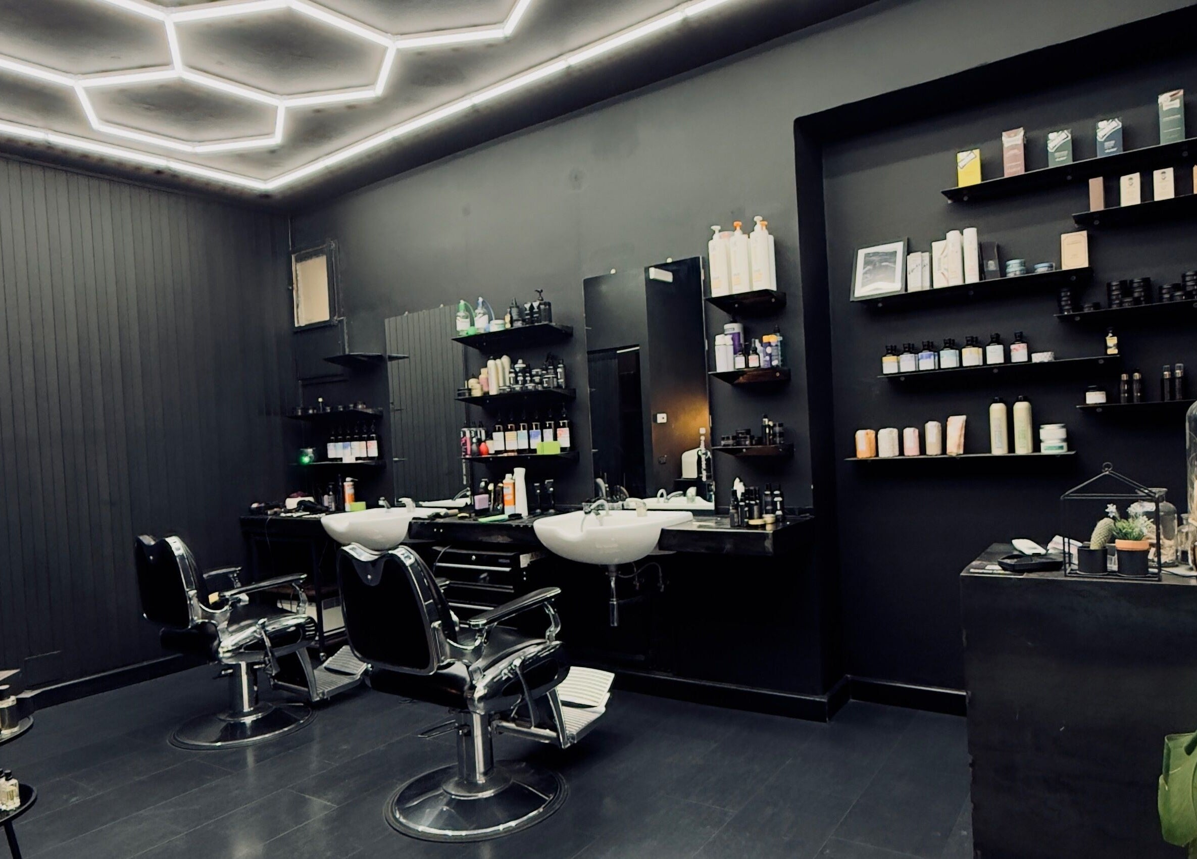 Interno moderno di Vogue Barber Shop, Arceto, Emilia-Romagna, IT con sedie e mensole elegantemente arredate.