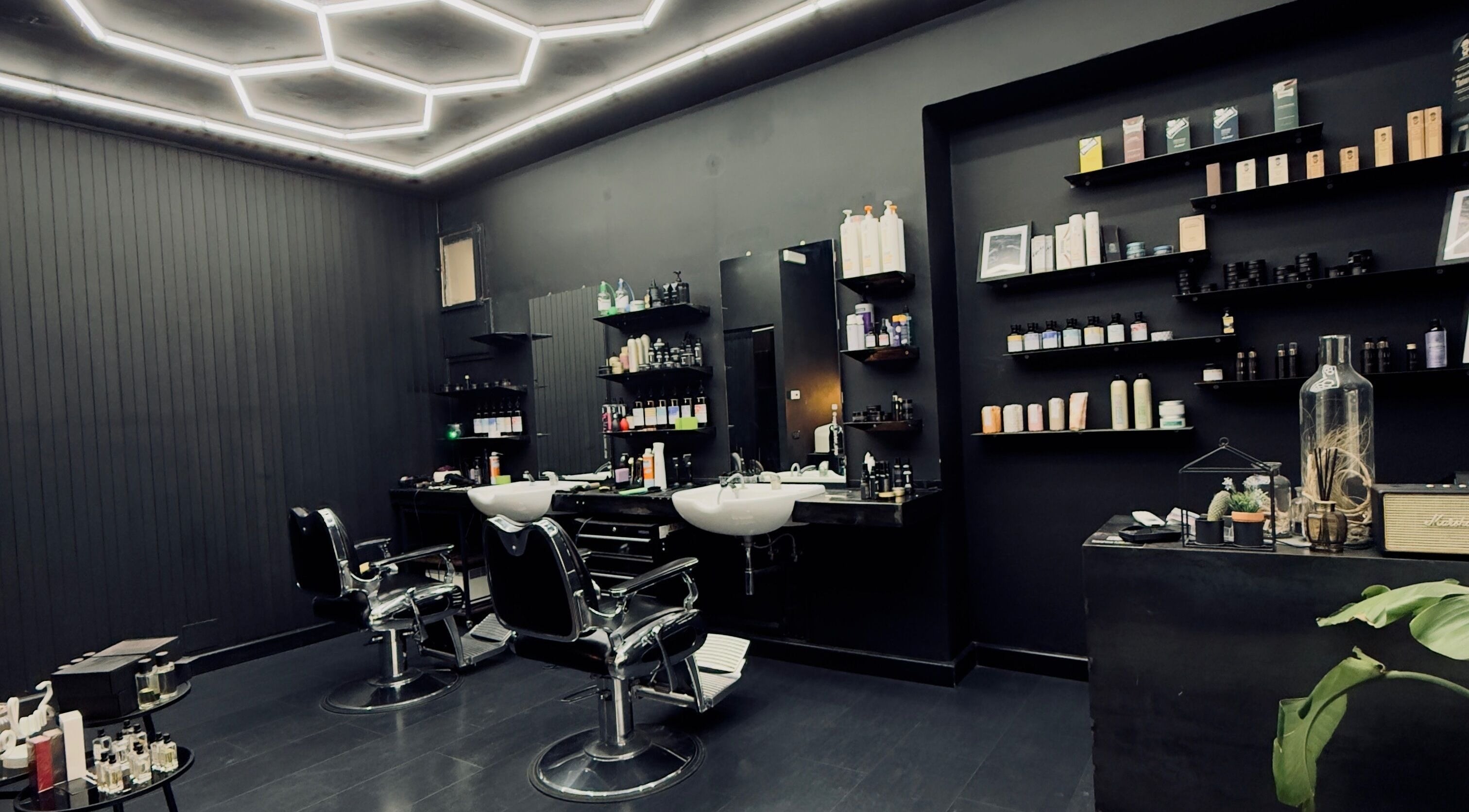 Interno moderno di Vogue Barber Shop, Arceto, Emilia-Romagna, IT con sedie e mensole elegantemente arredate.