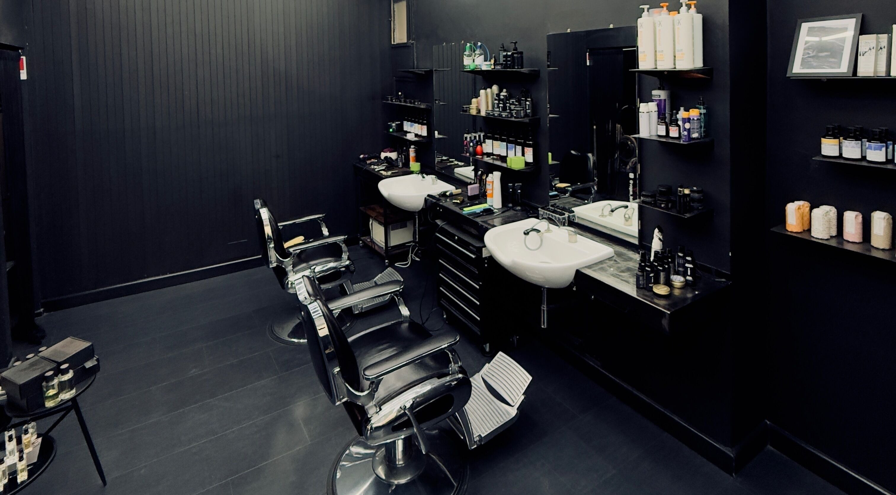 Interno moderno di Vogue Barber Shop, Arceto, Emilia-romagna, IT con poltrone eleganti e prodotti professionali.
