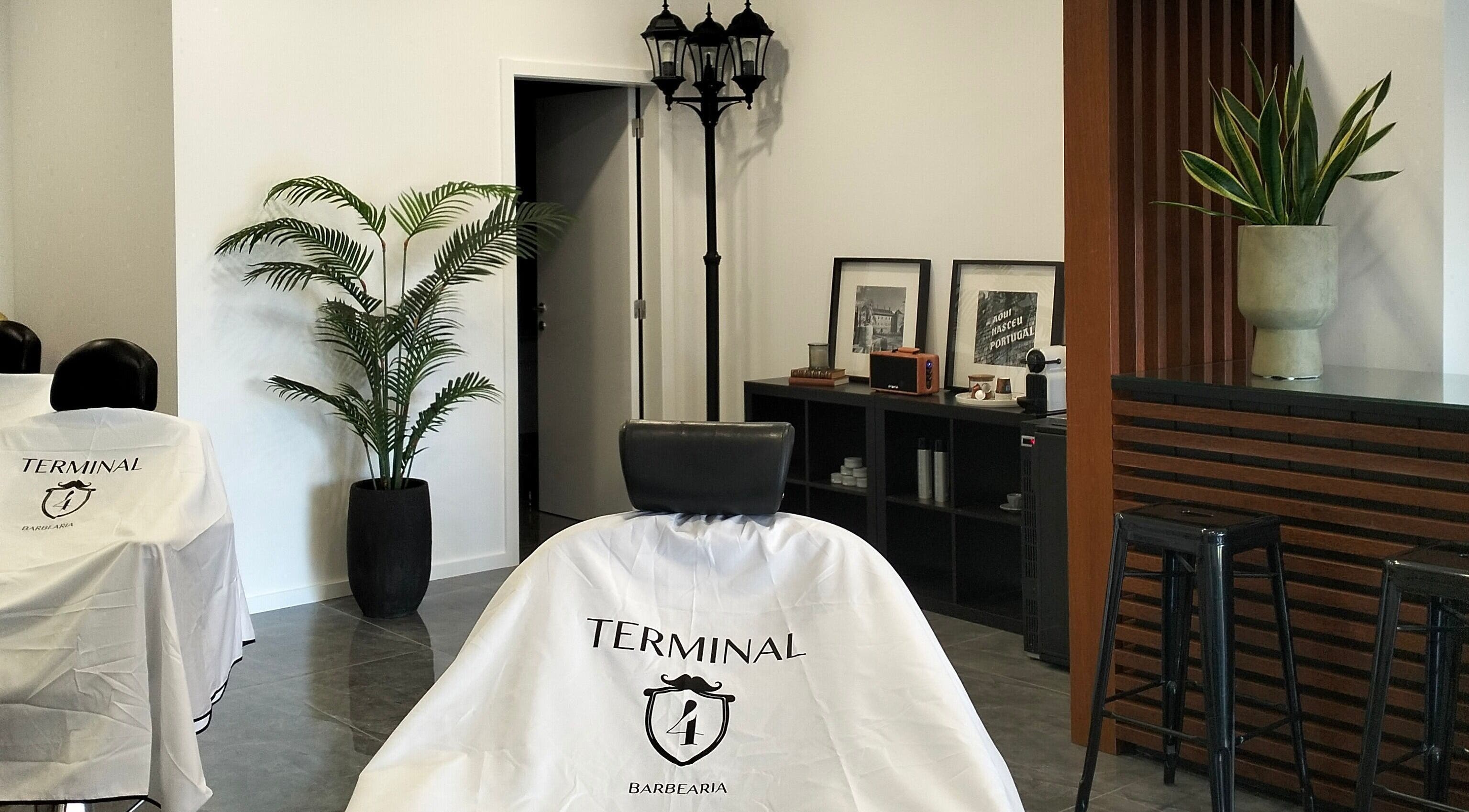 Interior moderno da barbearia Terminal4 em Guimarães, Braga, PT, com plantas e decoração elegante.