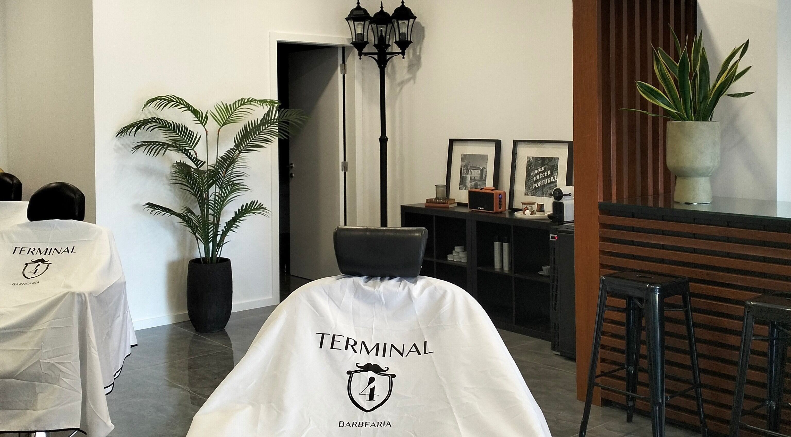 Interior moderno da barbearia Terminal4 em Guimarães, Braga, PT, com plantas e decoração elegante.