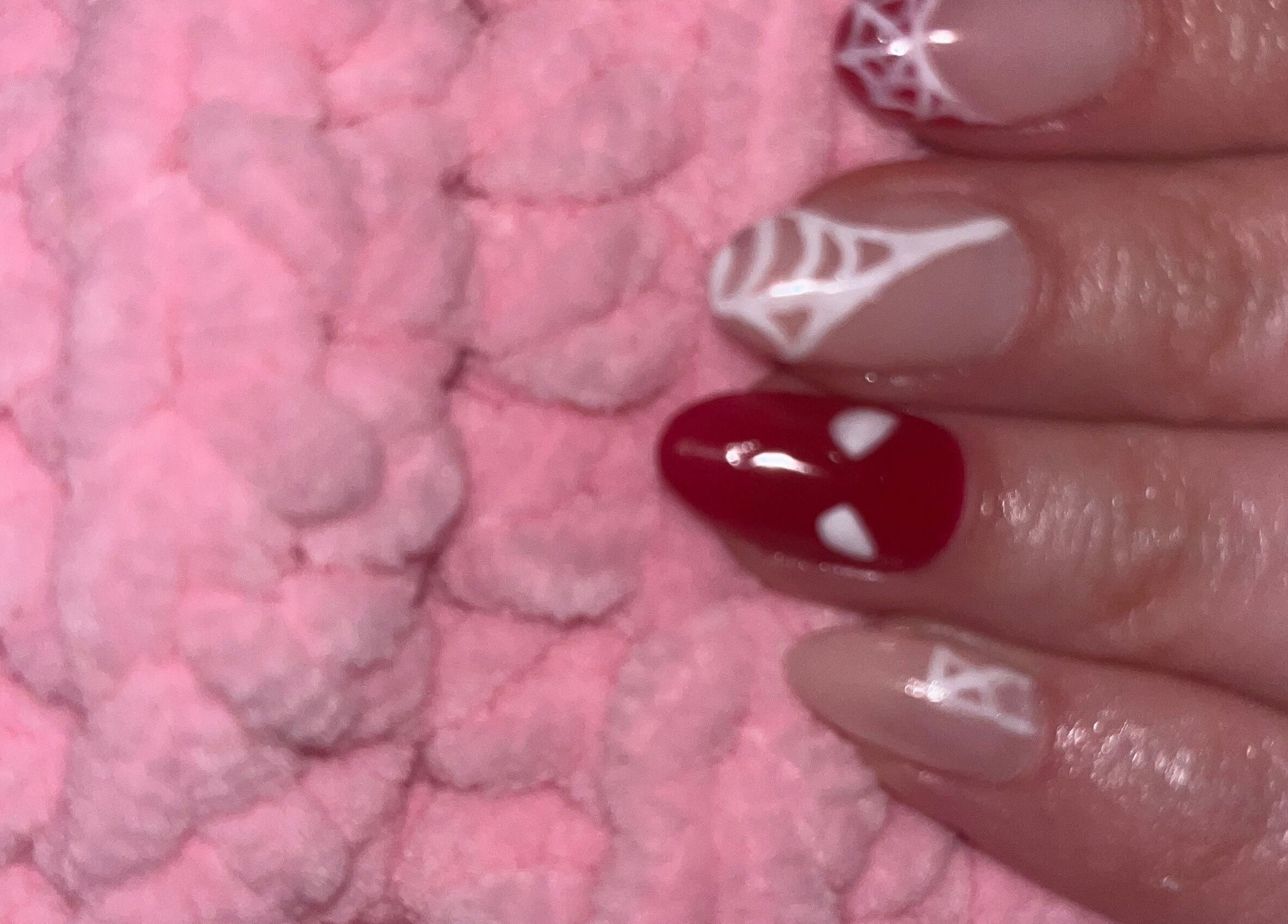 Intricate nail art featuring red and white designs at Glam Bar Ampthill, Ampthill, England, GB.