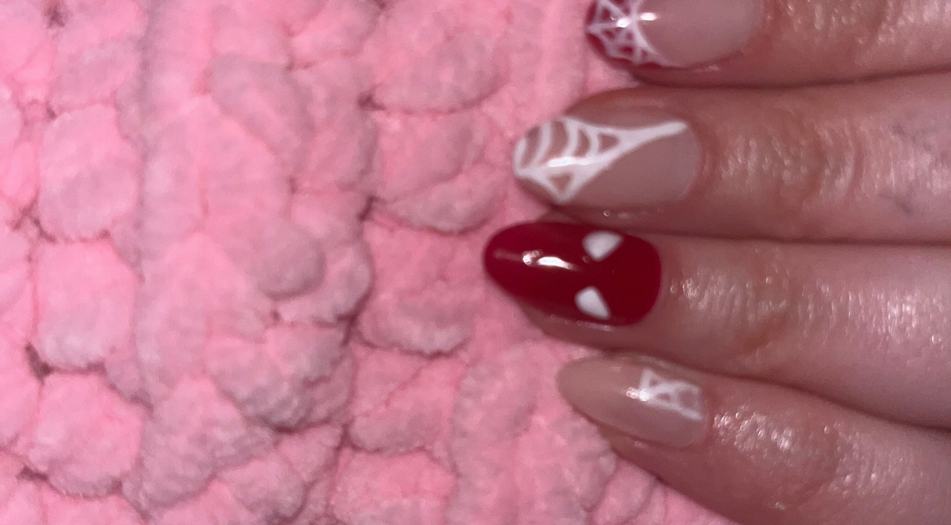 Intricate nail art featuring red and white designs at Glam Bar Ampthill, Ampthill, England, GB.