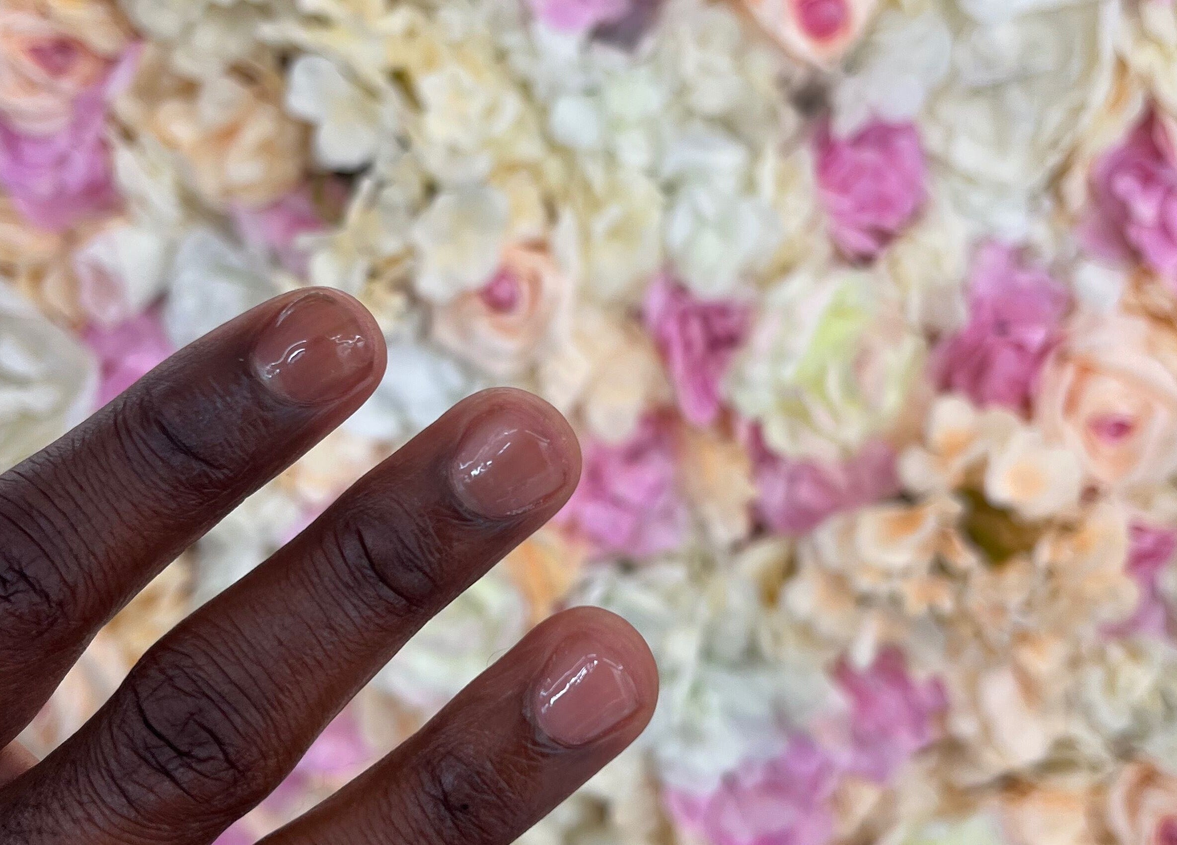 Elegant manicure showcased against a floral wall at Glam Bar Ampthill, Ampthill, England, GB.