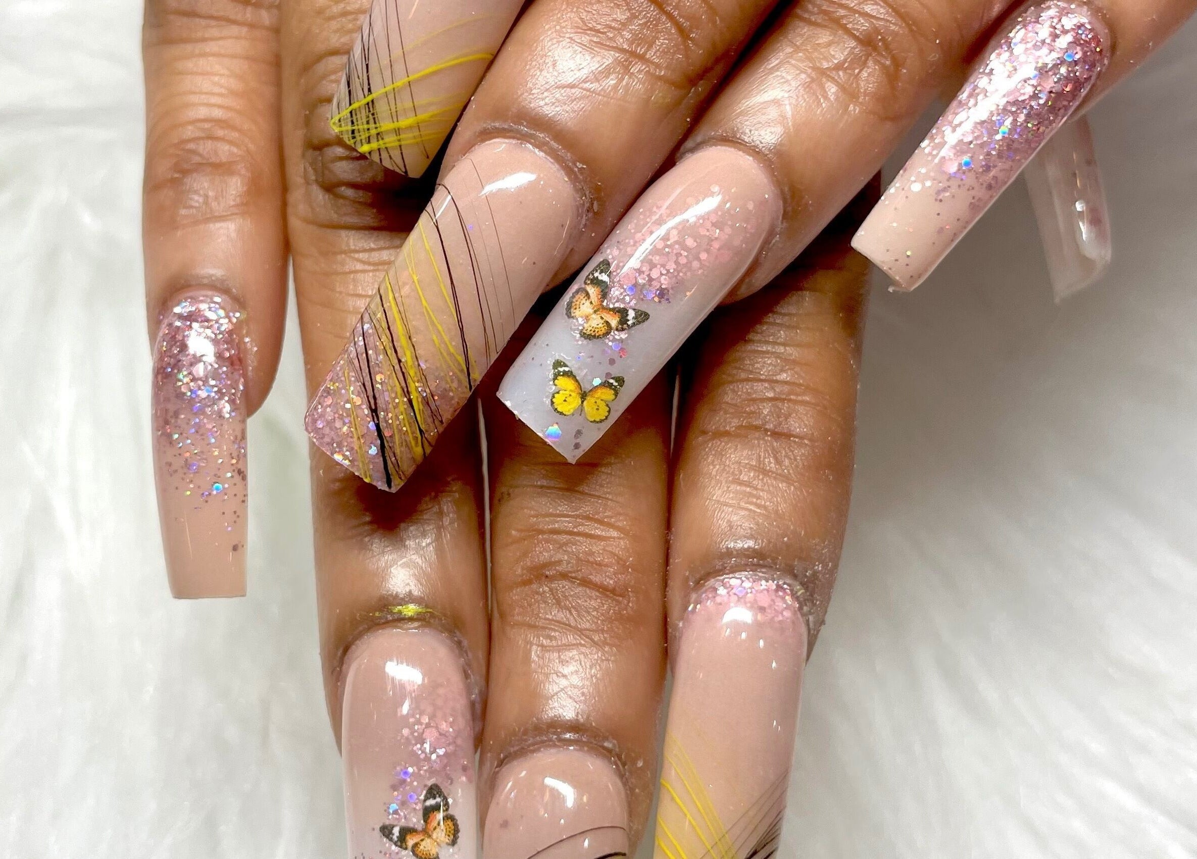 Elegant butterfly nail art at Aladdin Nails & Spa, Ocoee, Florida, US, with glittery accents.