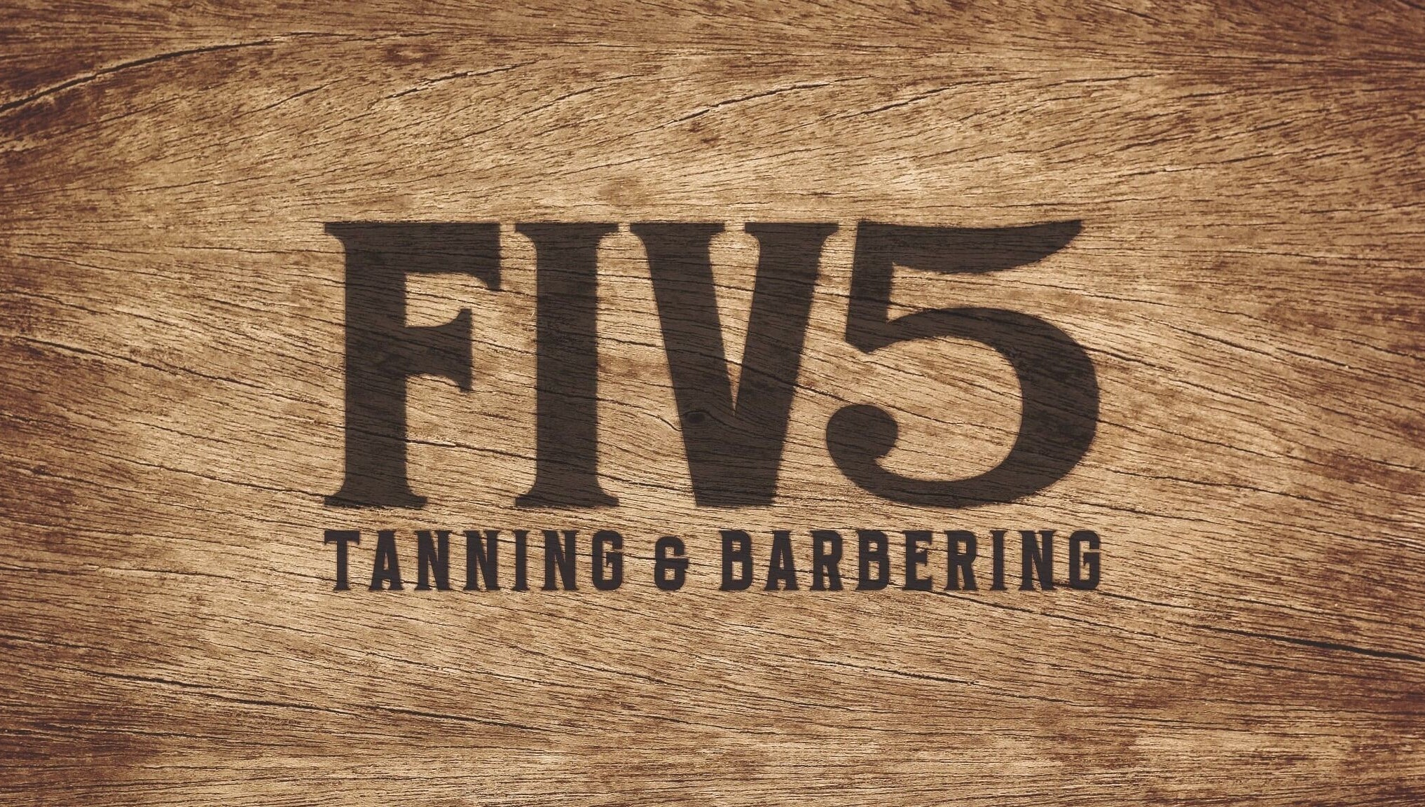 FIV5 Tanning & Barbering logo on wood texture, Sandy, England, GB.